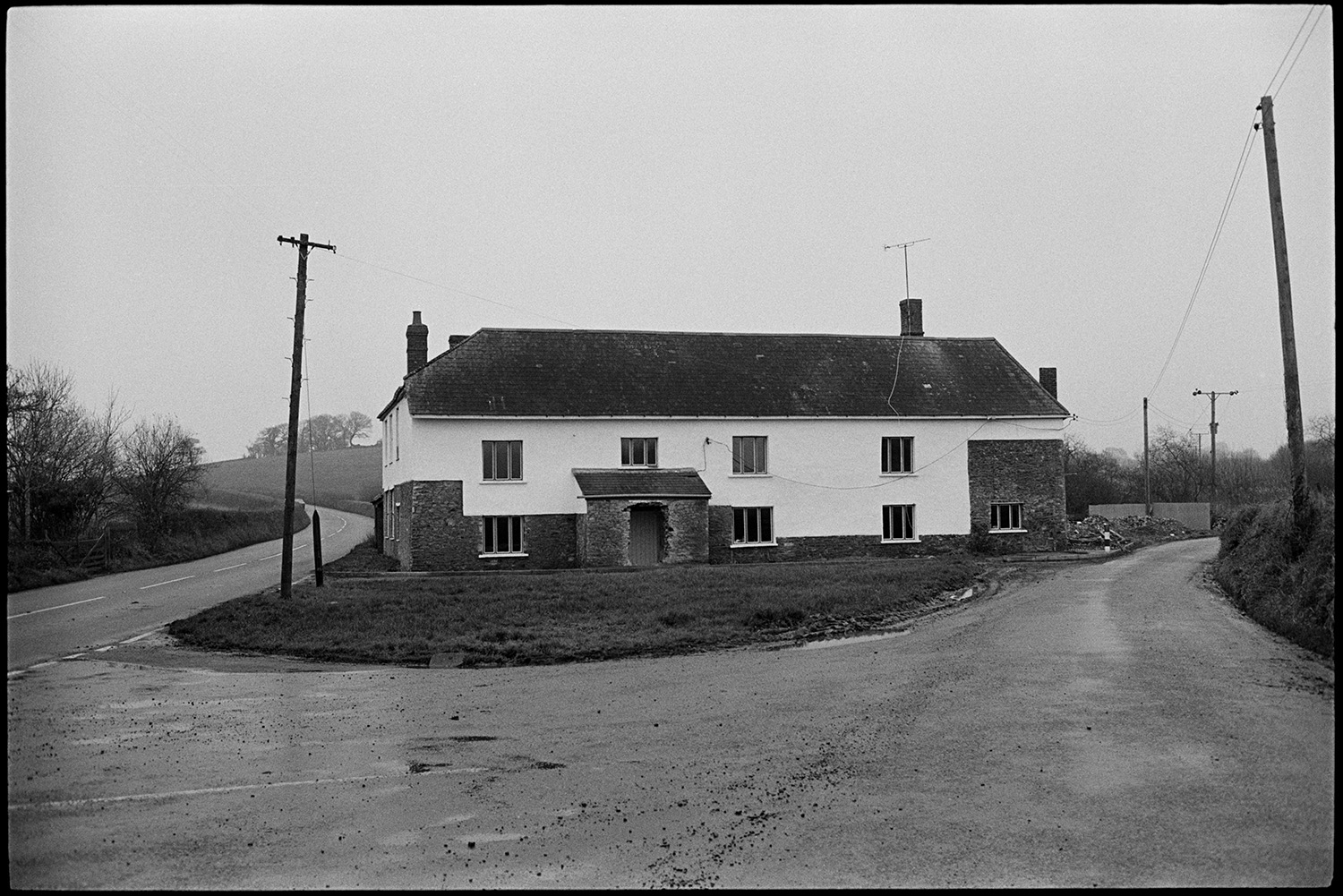 Large house beside road, completely ruined by tasteless modernisation, former inn?
[A large stone built house in the process of refurbishment, possibly a former inn, standing at a road junction near Taw Green, Winkleigh.]