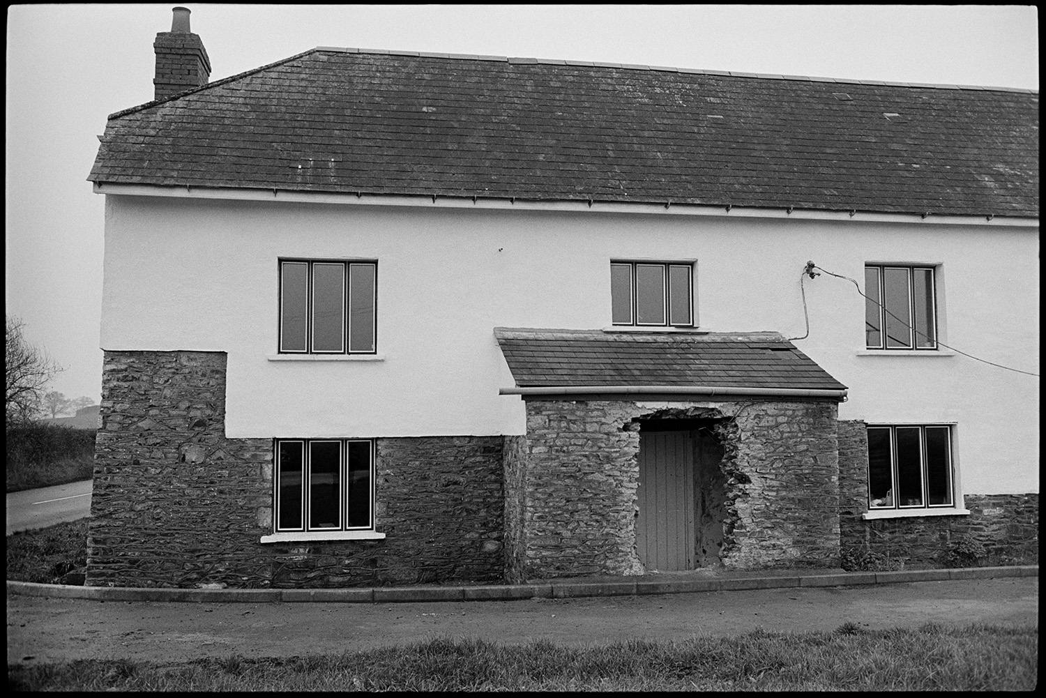 Large house beside road, completely ruined by tasteless modernisation, former inn?
[A large stone built house in the process of modernisation, possibly a former inn, standing at a road junction near Taw Green, Winkleigh.]