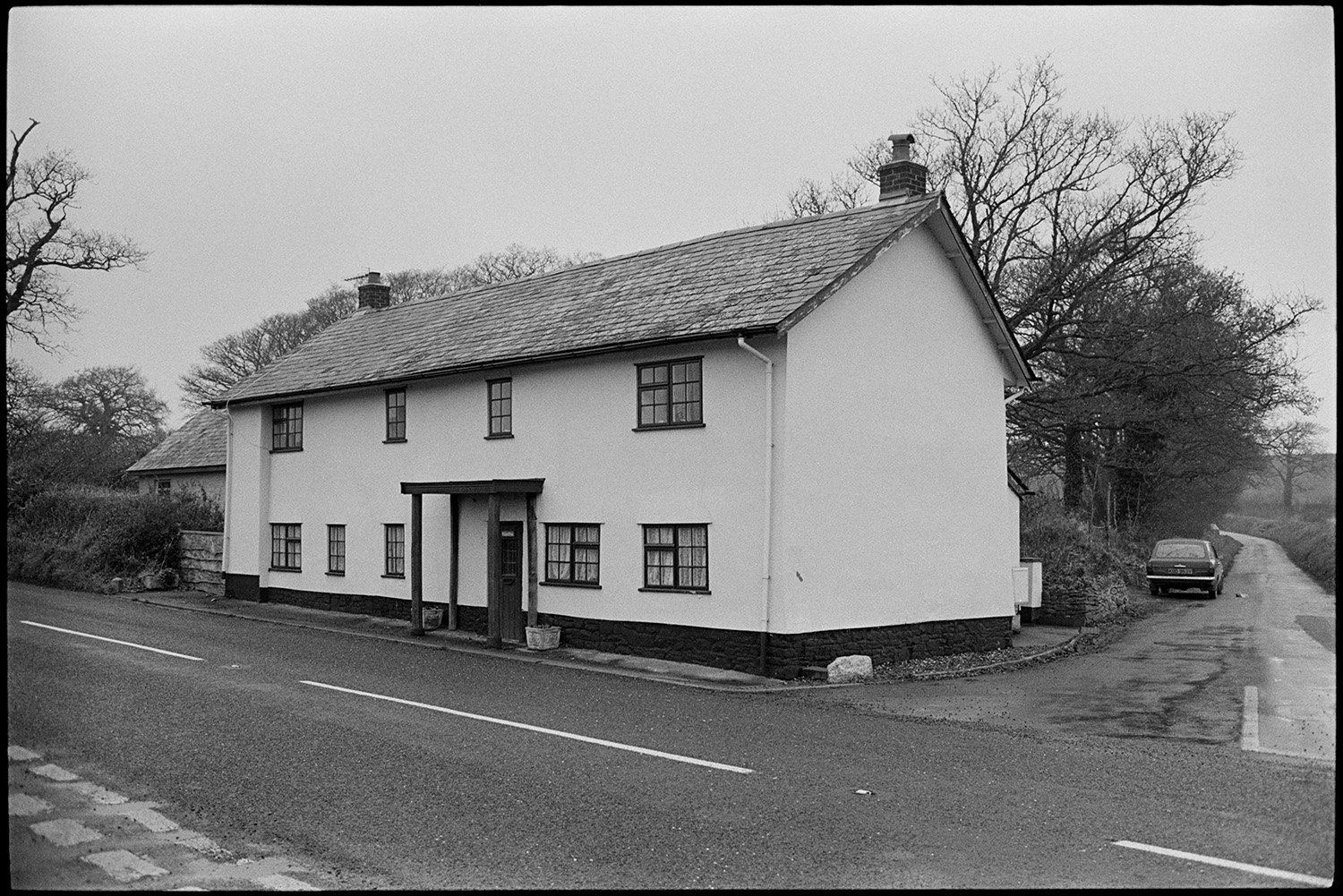 Modernised cottage, see photo in old archive before it was ruined!
[A large modernised cottage at Stopgate Cross near Zeal Monachorum. The cottage is whitewashed, with a porch with wooden supports, and a slate roof. A car is parked on the corner of the road leading to Lapford.]