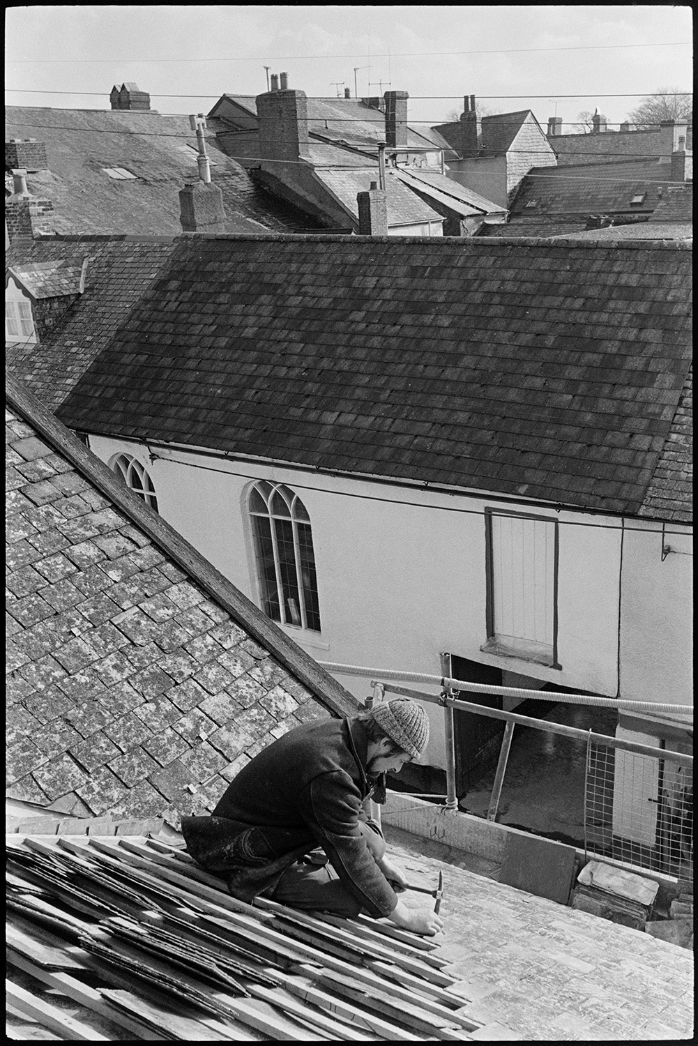 Builders re-slating roof and building dormer window.
[Chris Hiscock re-slating the roof of Western House, New Street, Chulmleigh. The work was done to create a dark room for James Ravilious. Other buildings can be seen in the background.]