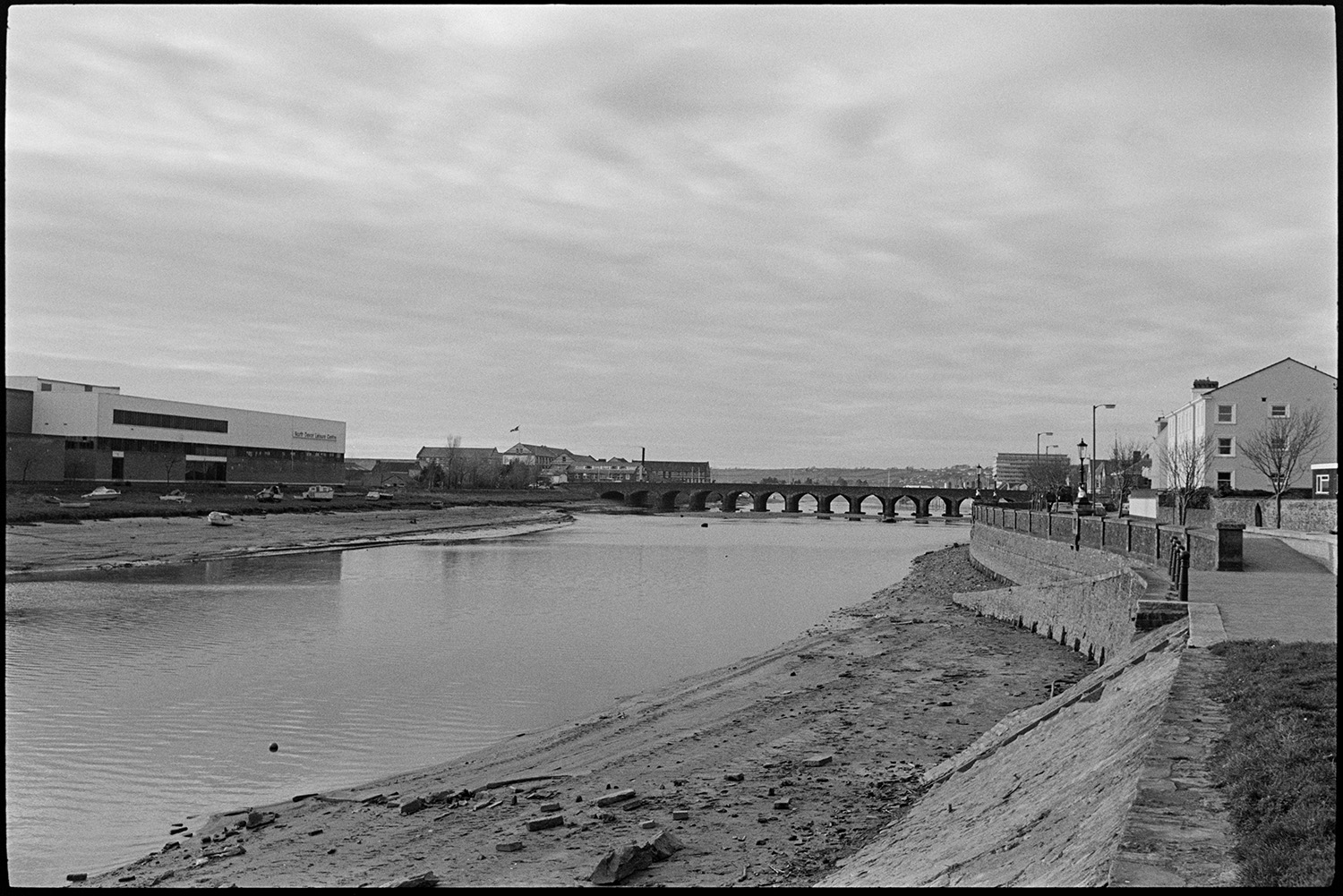 Towpath and bridge over Taw.
[View of the River Taw looking West towards the Long Bridge at Barnstaple with the North Devon Leisure Centre on the southern bank.]