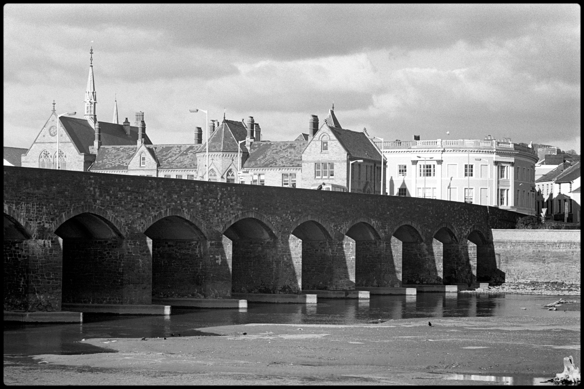 View of old bridge across to Victorian buildings. <br />
[Barnstaple Bridge across the river Taw at Barnstaple. Victorian buildings can be seen on the opposite side of the river.]