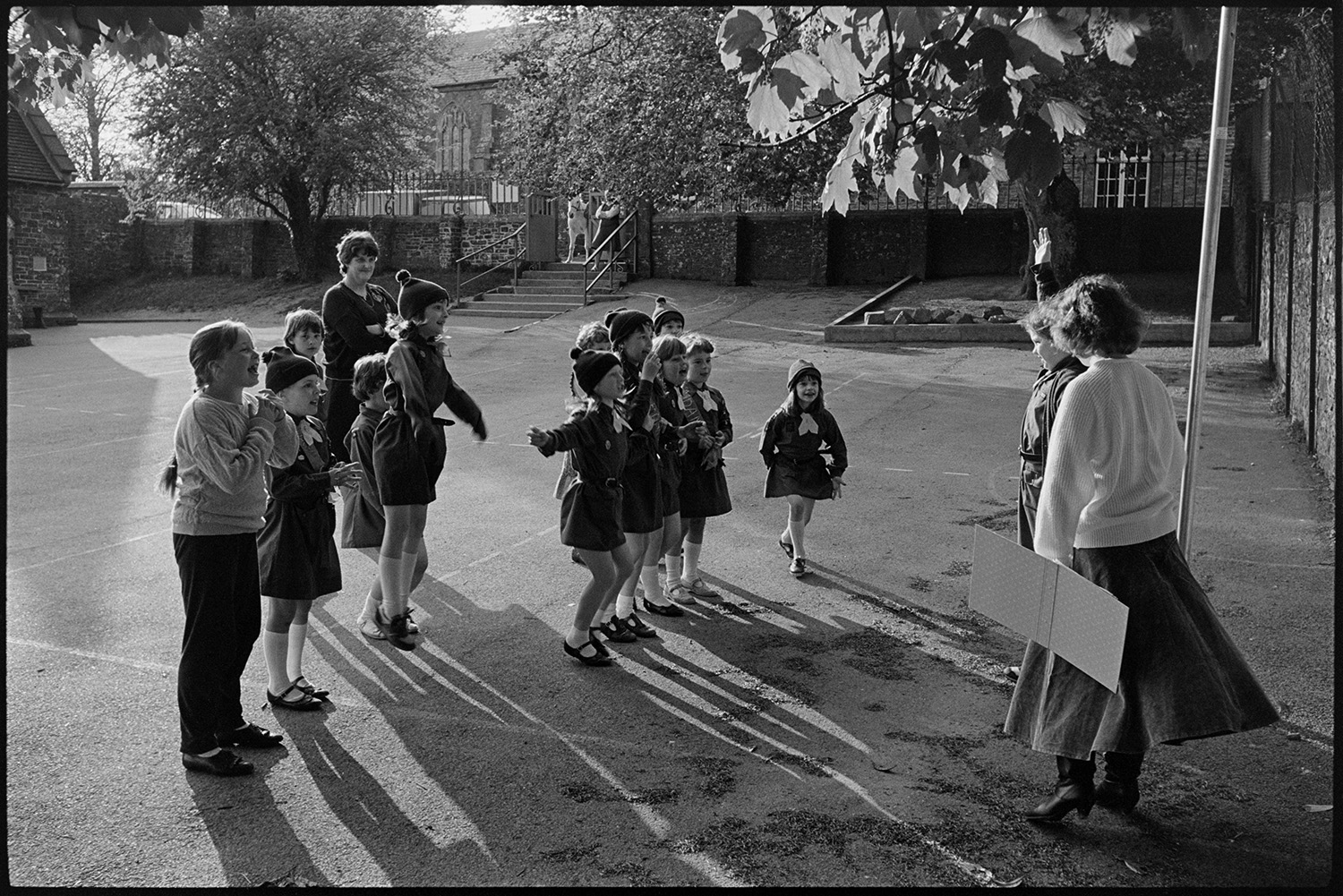Brownies roll call in school playground.
[Pip Gilson with a group of Brownies doing a roll call in the playground at Chulmleigh Primary School.]