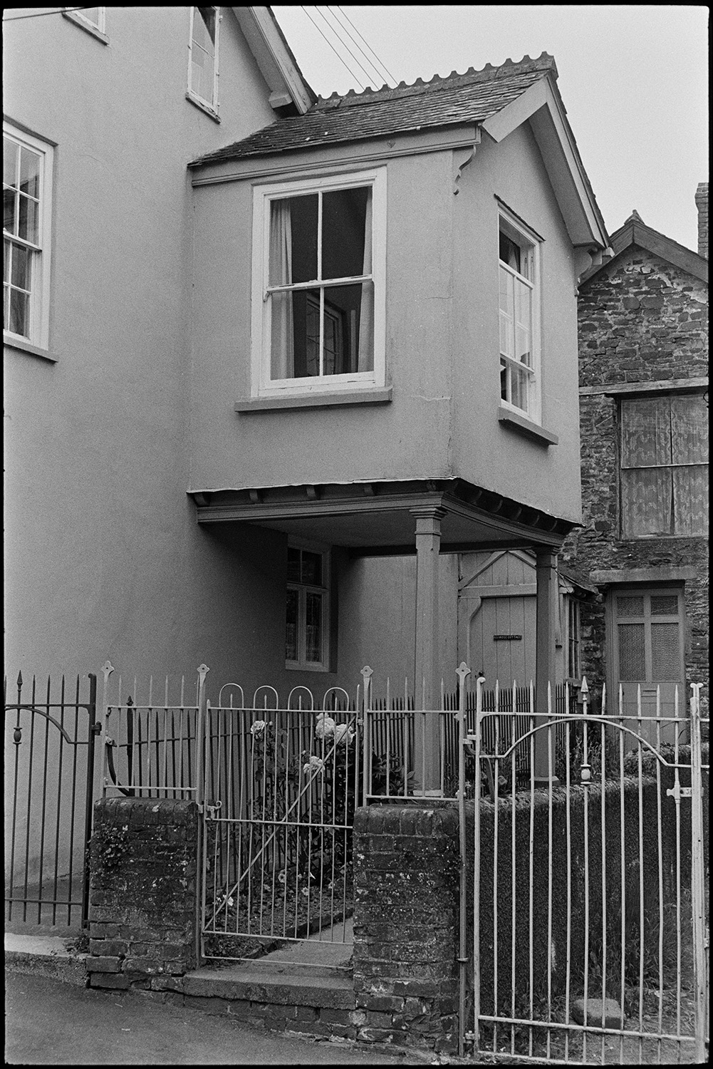 Street scenes with people and cars. 
[Small first floor extension supported by pillars on the side of a house in Chulmleigh.]