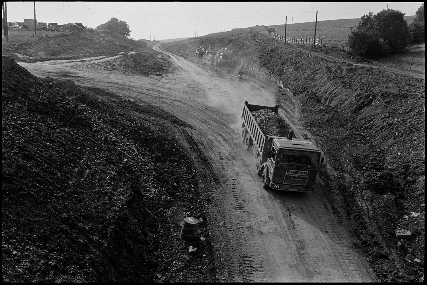 Site of new link road along old railway line. Stone bridge before demolition. Surveyor.<br />
[A lorry working at the construction site, near South Molton, of the North Devon Link road. It is moving earth.]