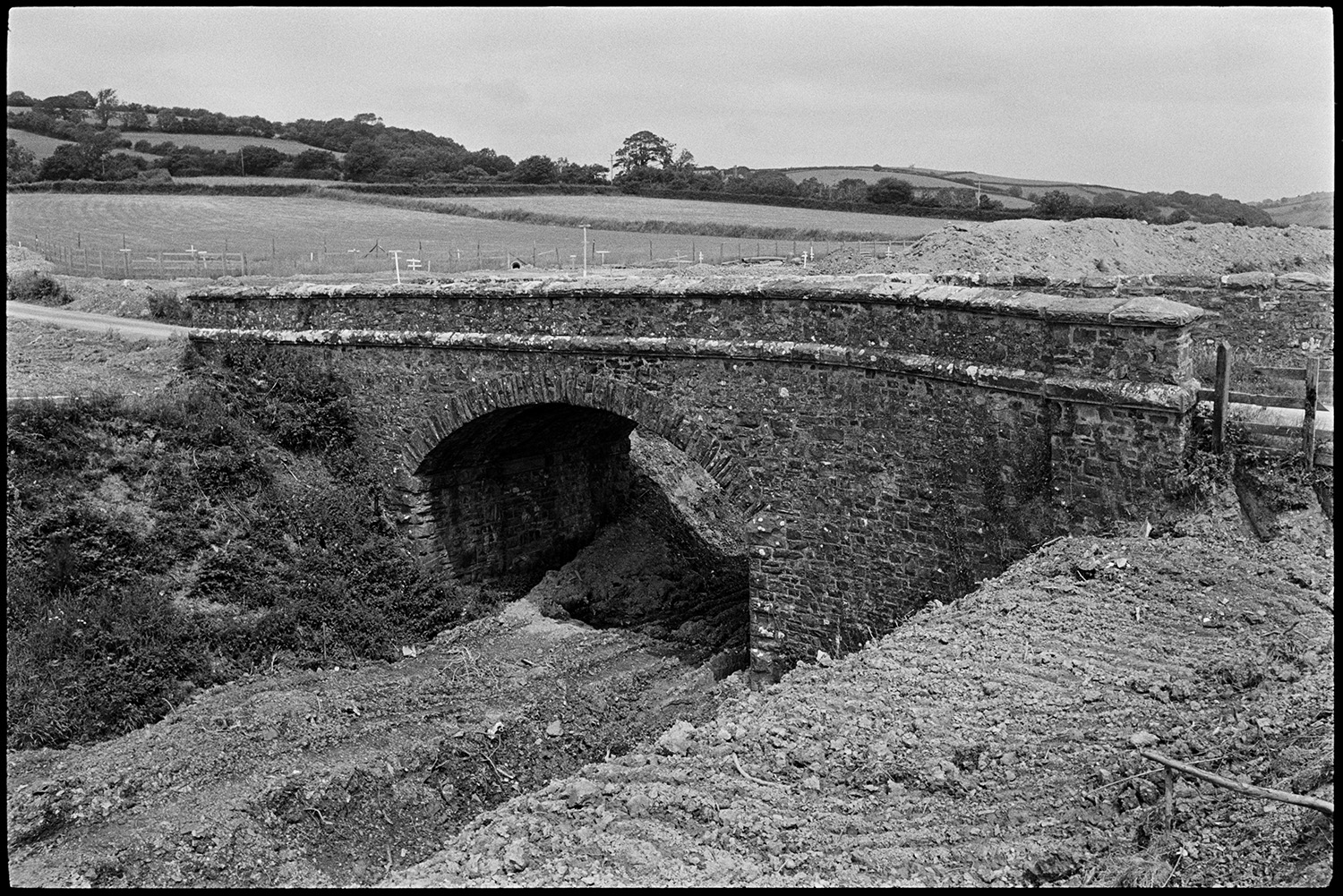 Site of new link road along old railway line. Stone bridge before demolition. Surveyor.<br />
[A bridge over the site of an old railway line near South Molton which is about to be demolished for the construction of the North Devon Link road.]
