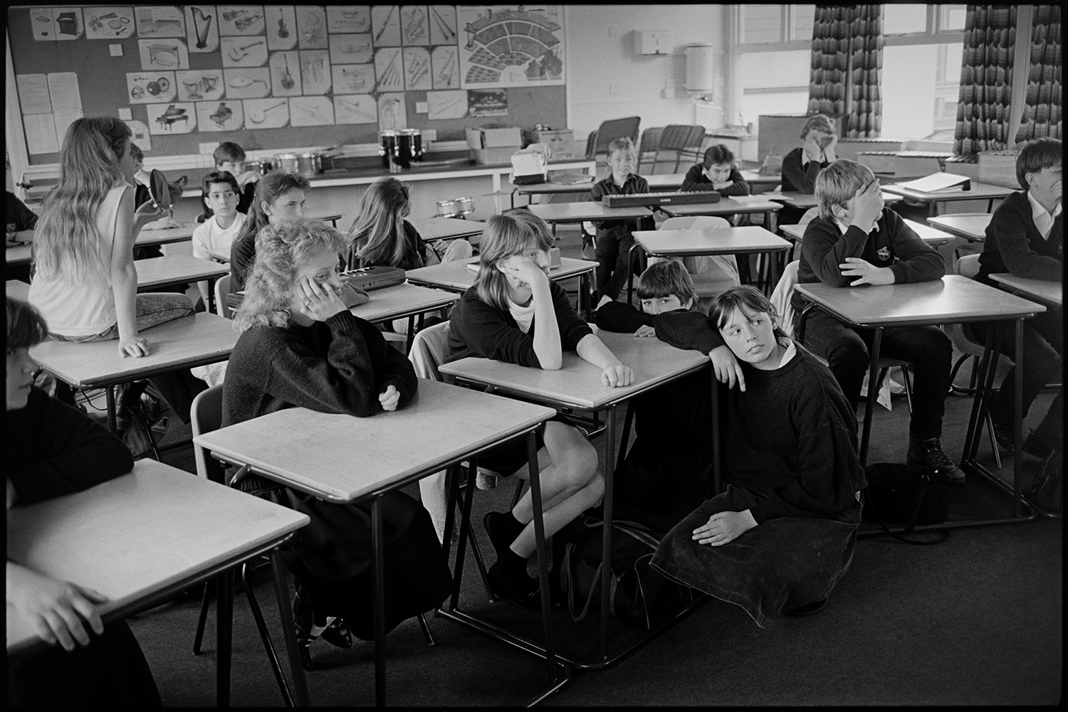 Classroom with pupils acting out short play with music. 
[Students sat at desks in a classroom at Chulmleigh Community College watching other pupils perform a short play.]