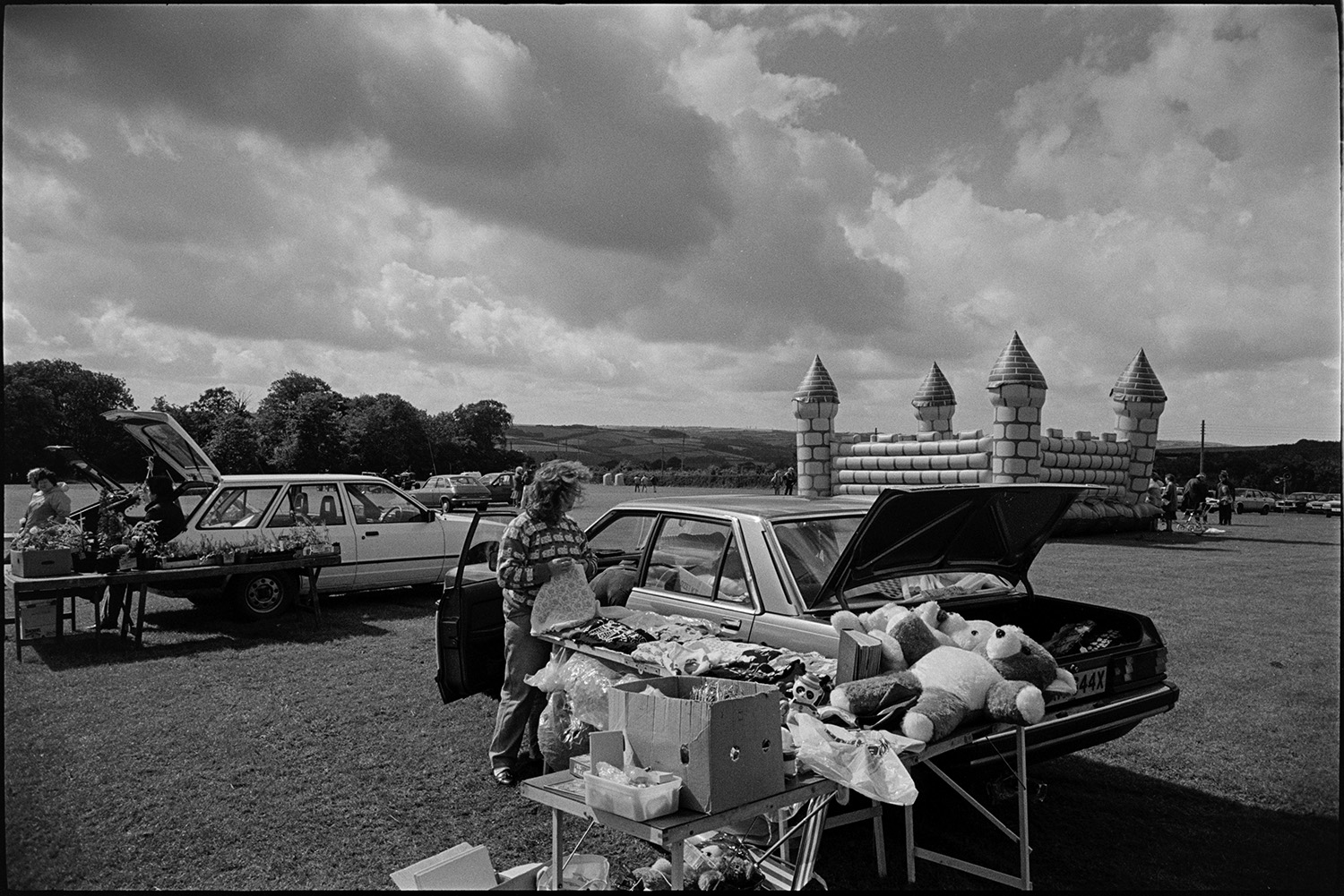 Sports Day, sheep dog trials, races, stalls, football. 
[People running stall at a car boot sale at a sports day in Chulmleigh playing field. A bouncy castle is visible in the background.]