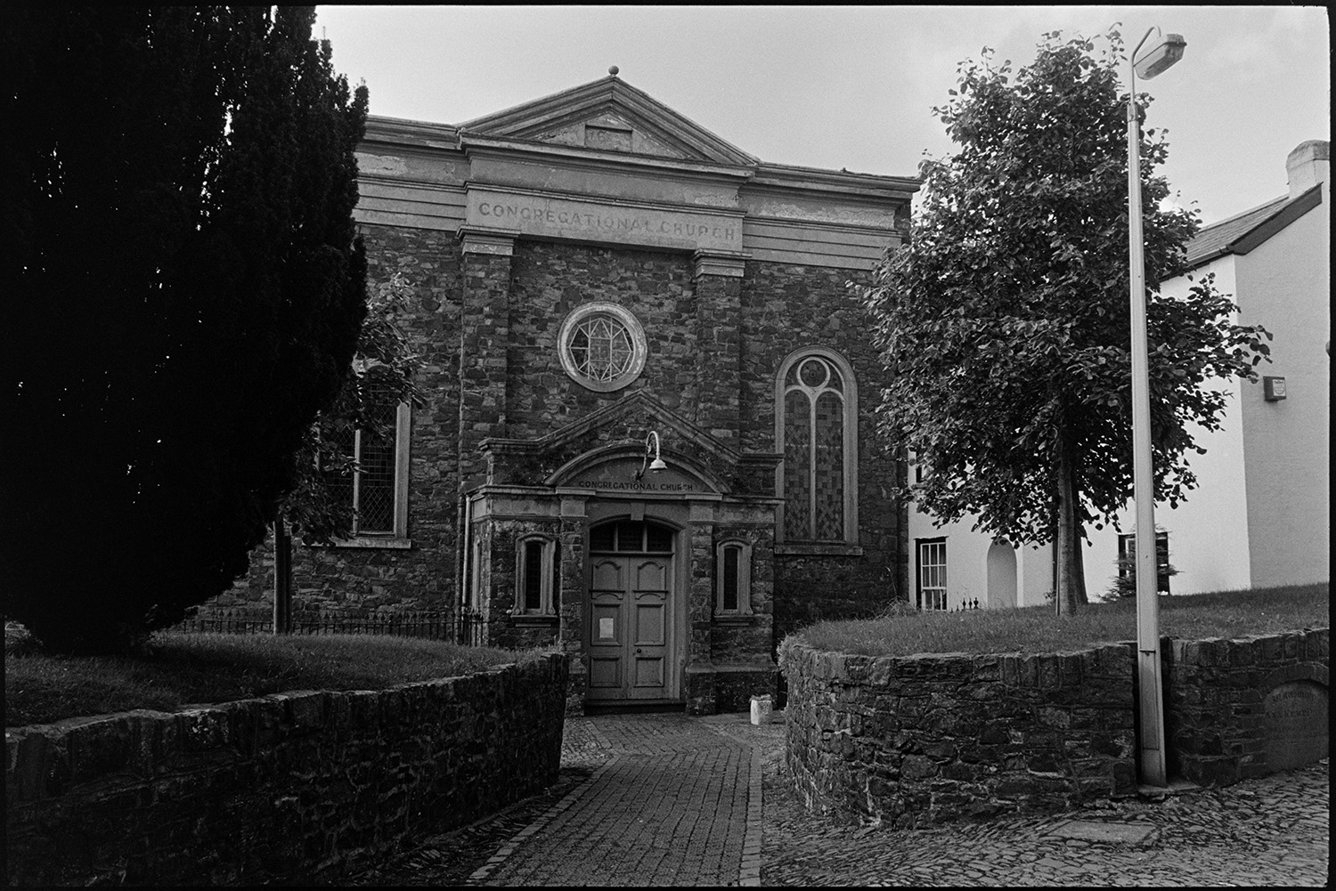 Chapel building. 
[The front of the Congregational Chapel in South Molton. A cobbled pathway leading to the chapel and stained glass windows are visible.]