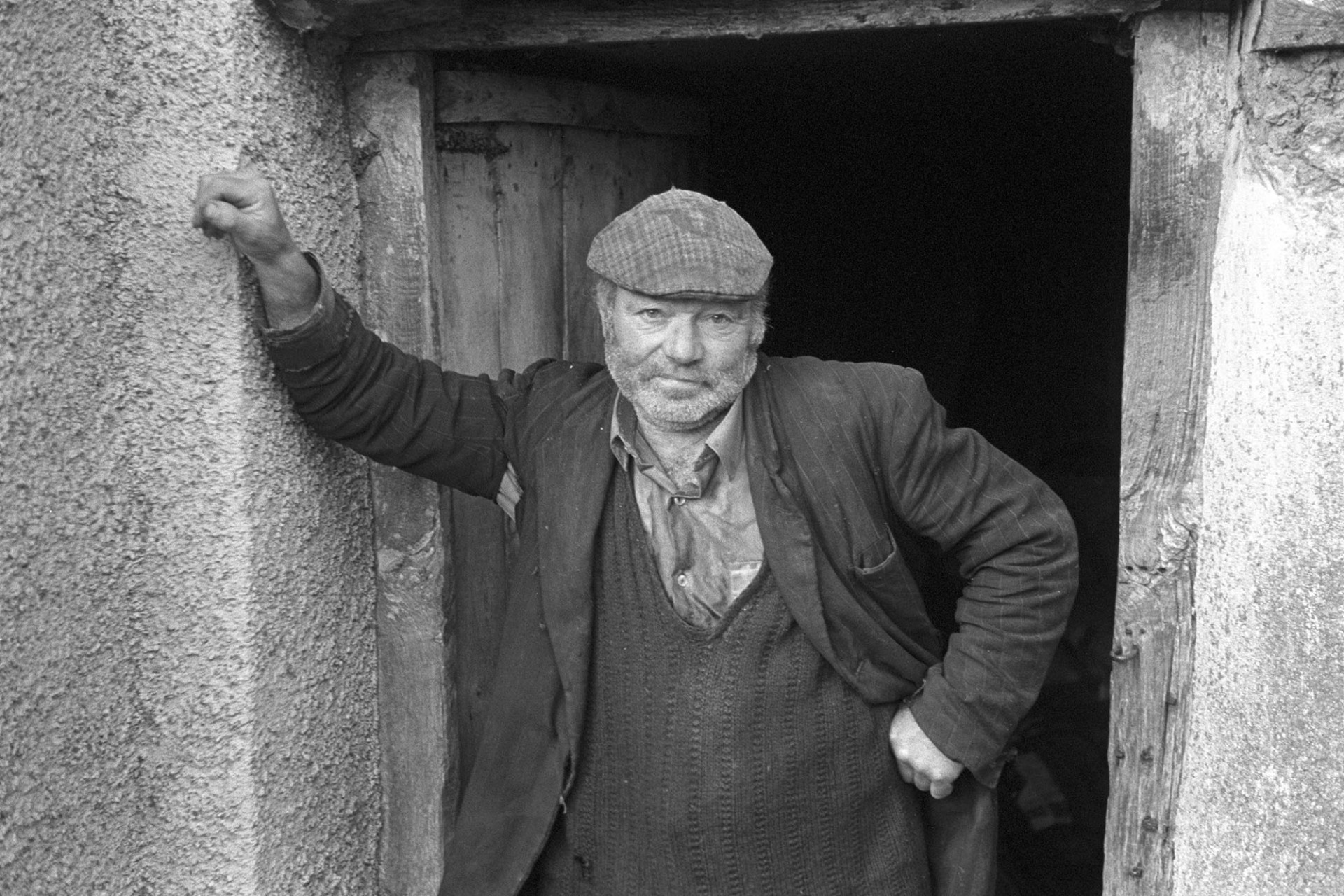 Orchards, Devon, man facing camera in doorway in cap. 
[Reg Holland stood in a wooden doorway wearing a cap, at Newhouse, Ashreigney.]