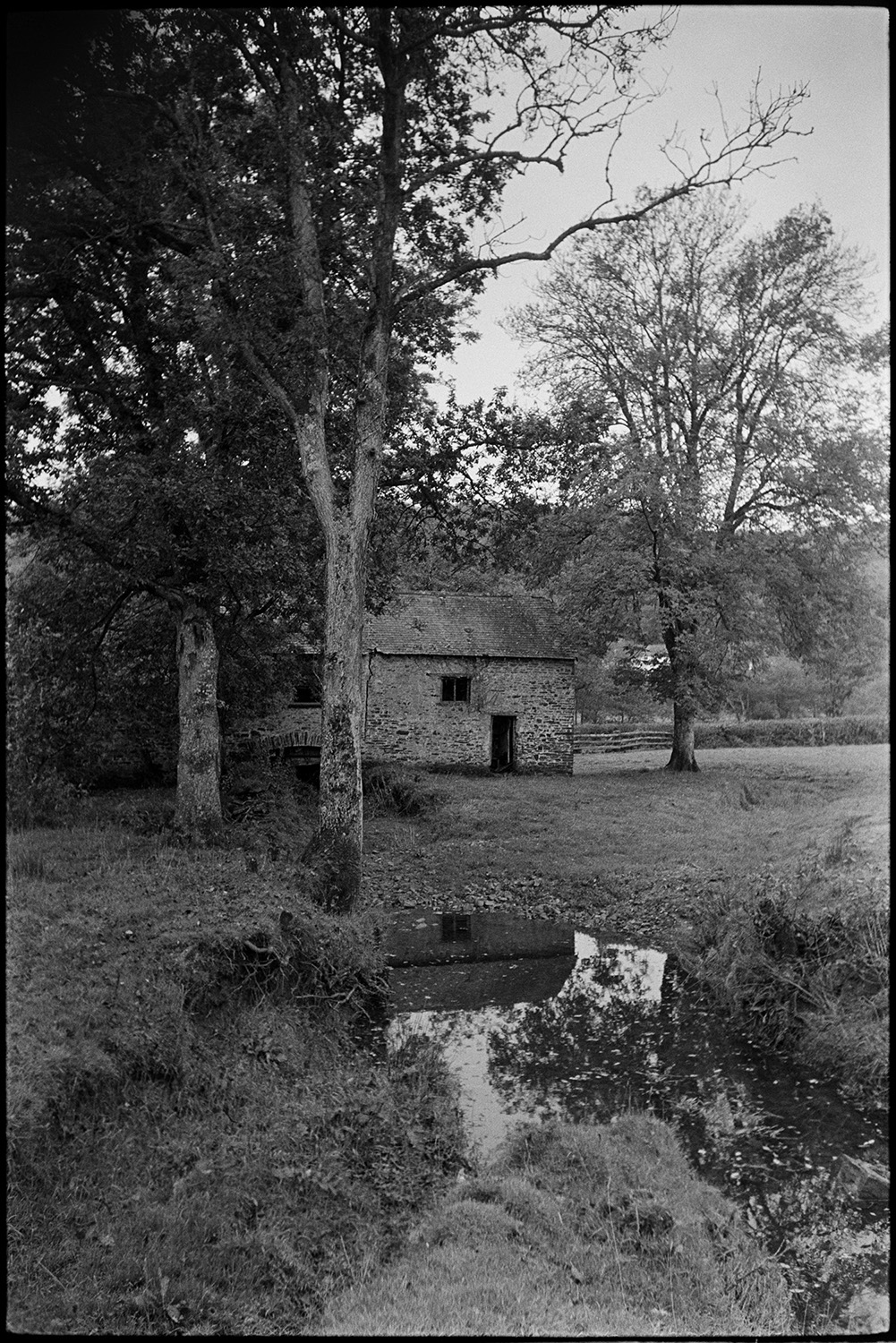 Old stone mill. 
[A stone mill building by the River Mole and field with trees at Cawseys Meethe, Kings Nympton.]
