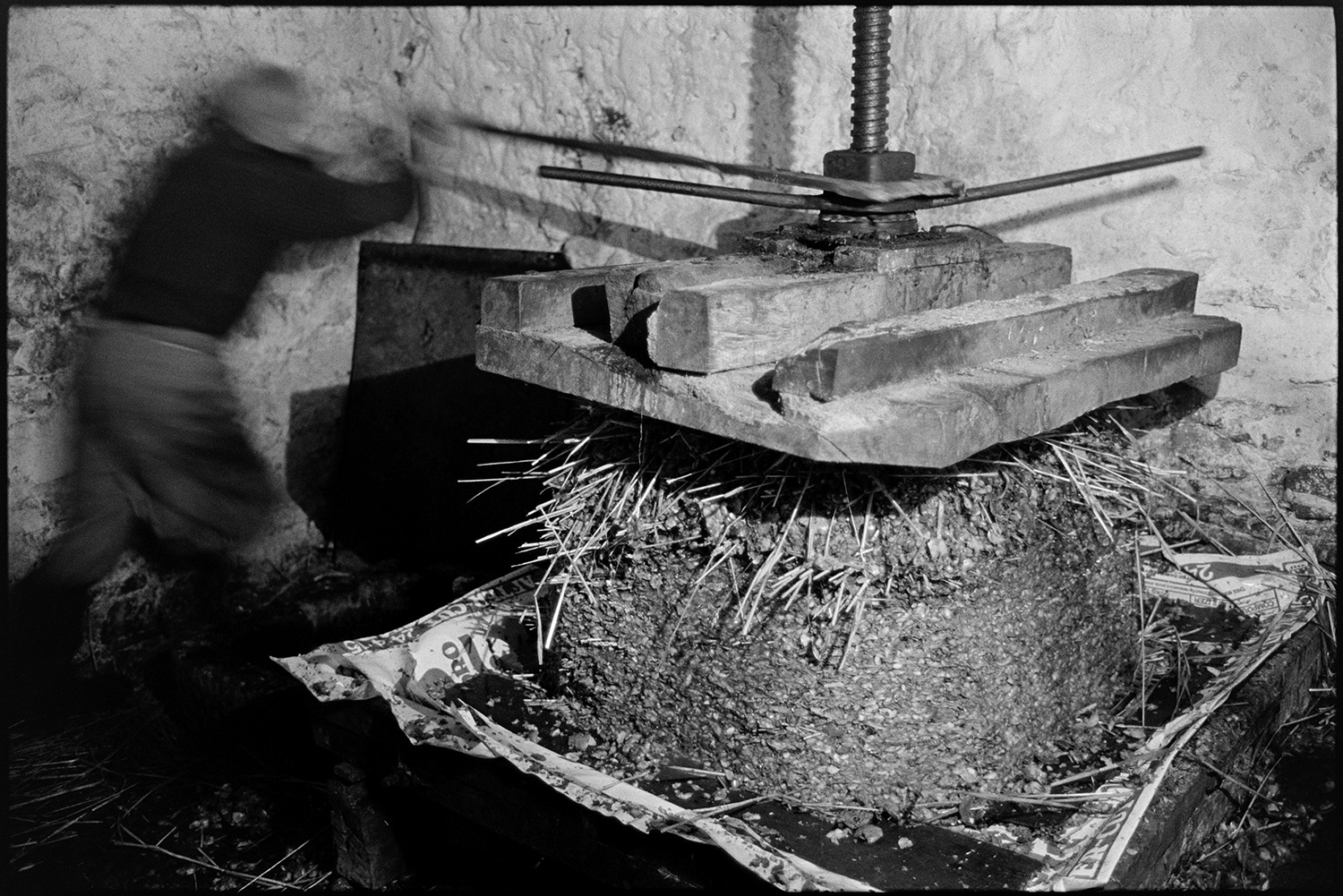 Cider making, man operating cider press. 
[Bill Hammond operating a cider press in a barn at Rashleigh Mill, Bridge Reeve. He is compressing the cheese, which is layers of apple pulp and straw.]
