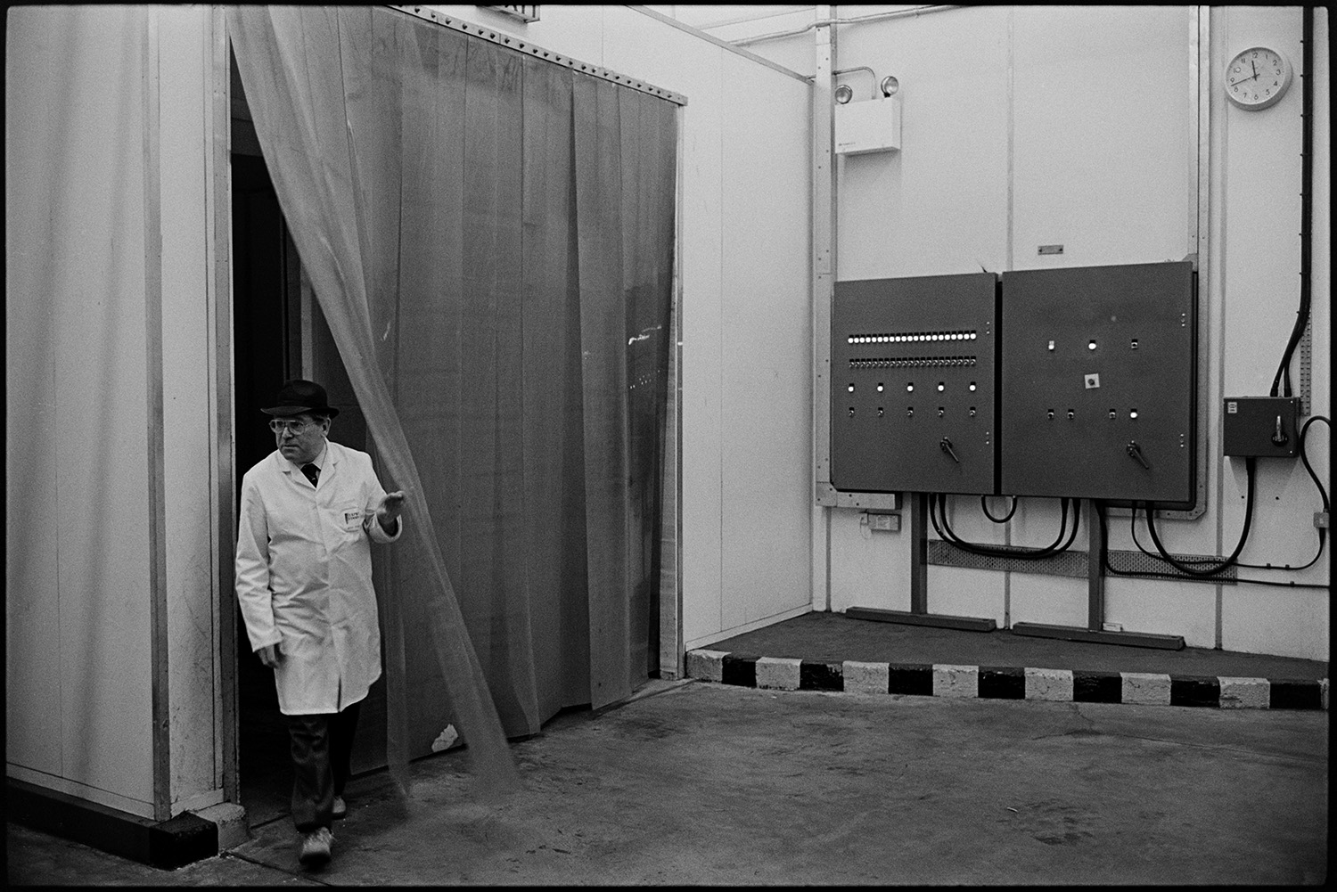 Men working in cheese factory. 
[A man walking through a polythene doorway a the Dairy Crest North Tawton Cheese Factory.]