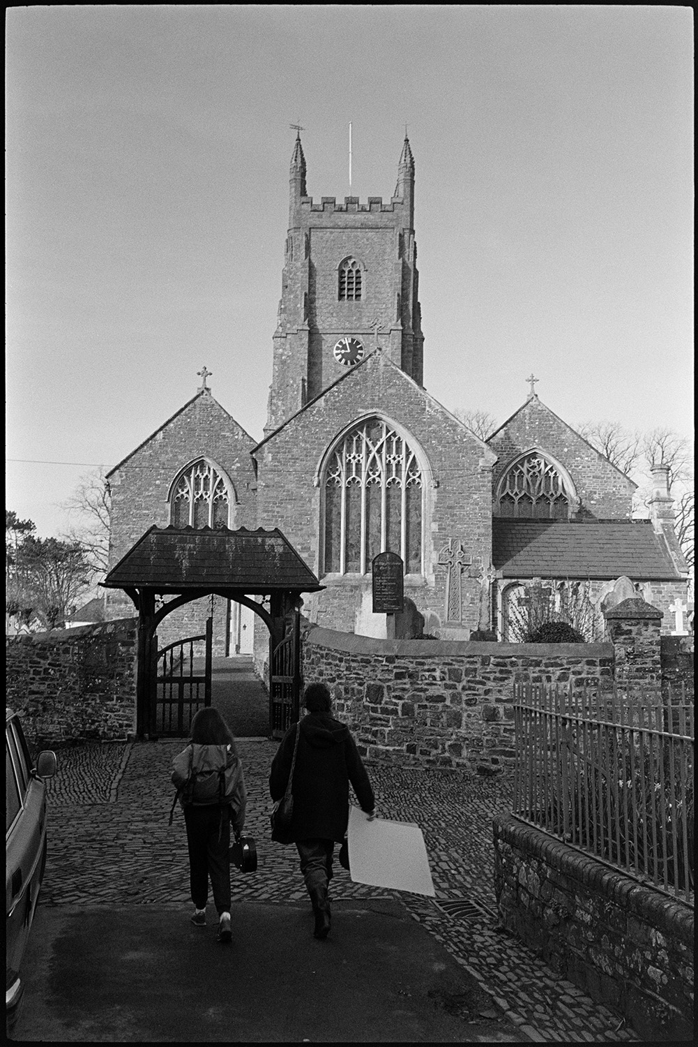 School children in playground playing in old school. 
[An adult and child walking along a cobbled path towards Chulmleigh Church, possibly after leaving Chulmleigh Primary School.]
