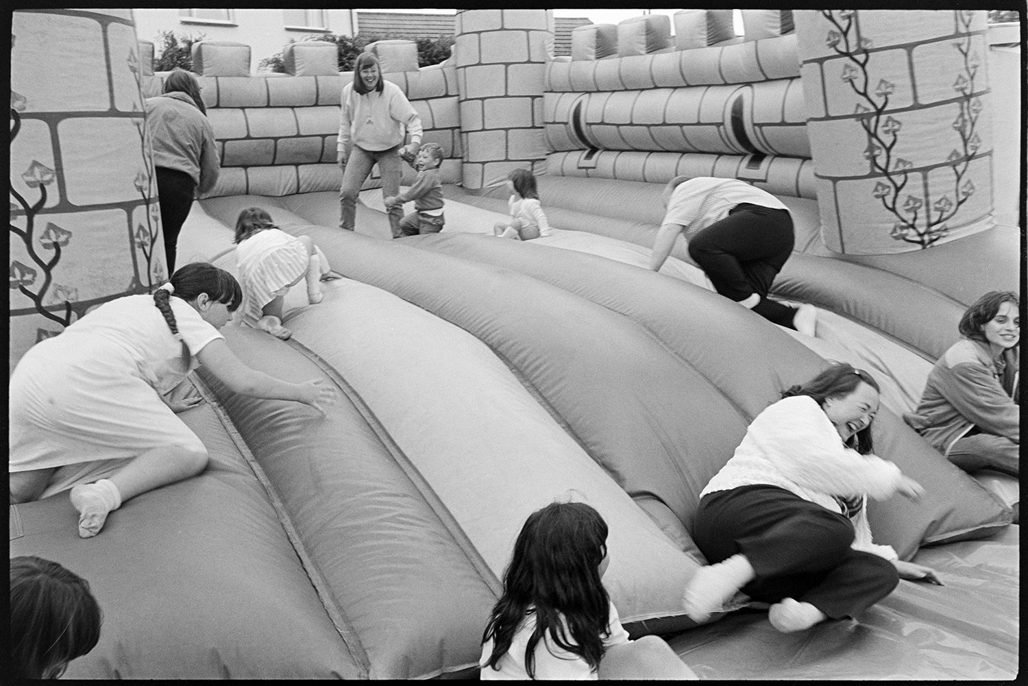 Village Club Day, sports, teas, clay pigeon shoot, committee in discussion.
[Children climbing and falling over on the bouncy castle at the Village Club Day at Chawleigh. A woman is supervising the children on the bouncy castle.]