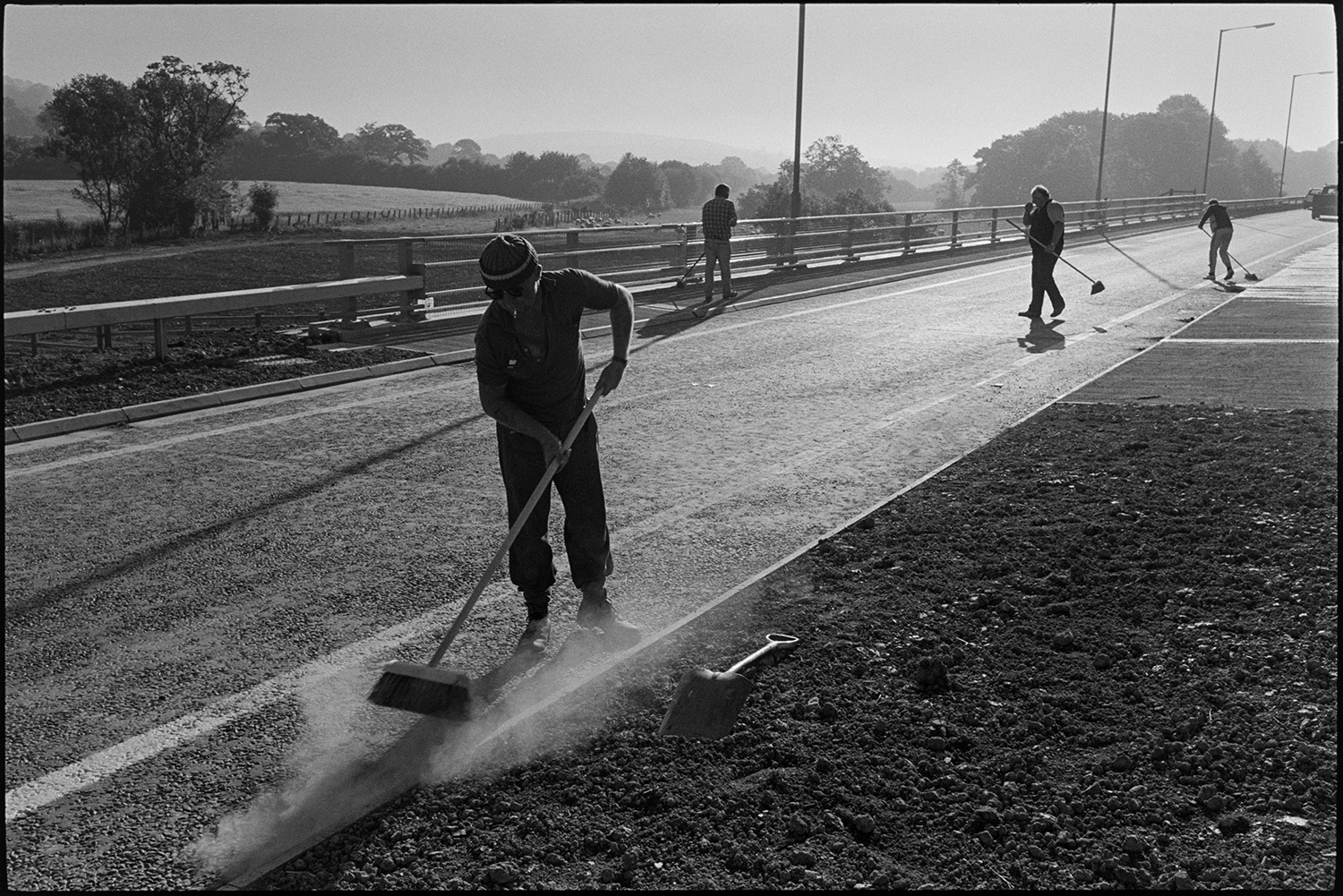 Men sweeping new link road before official opening.
[Four men sweeping the A361 North Devon Link Road near South Molton before the official opening.]