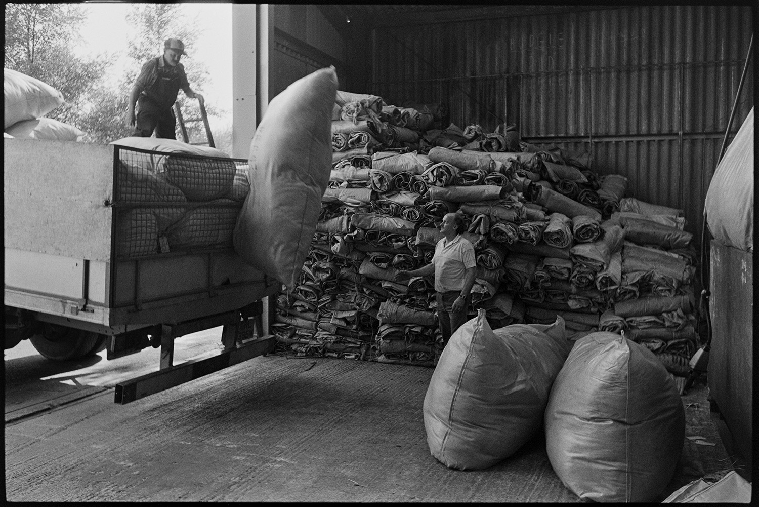 Two men unloading large bags of wool from a truck into the warehouse of Devon & Cornwall Wools Ltd at the Pathfields Business Park in South Molton.