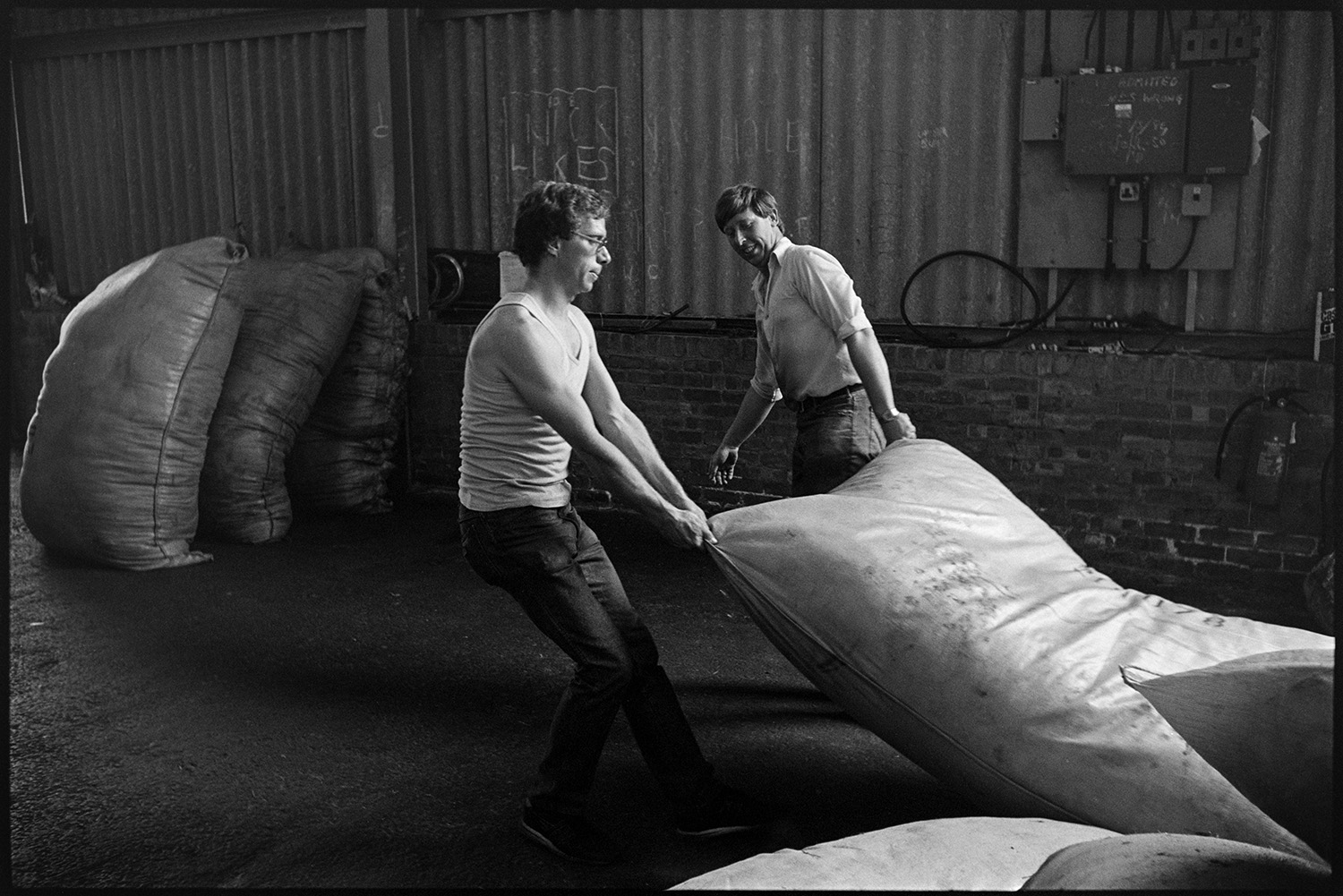 Two men dragging a large bag of wool into the warehouse of Devon & Cornwall Wool Ltd at the Pathfields Business Park in South Molton.