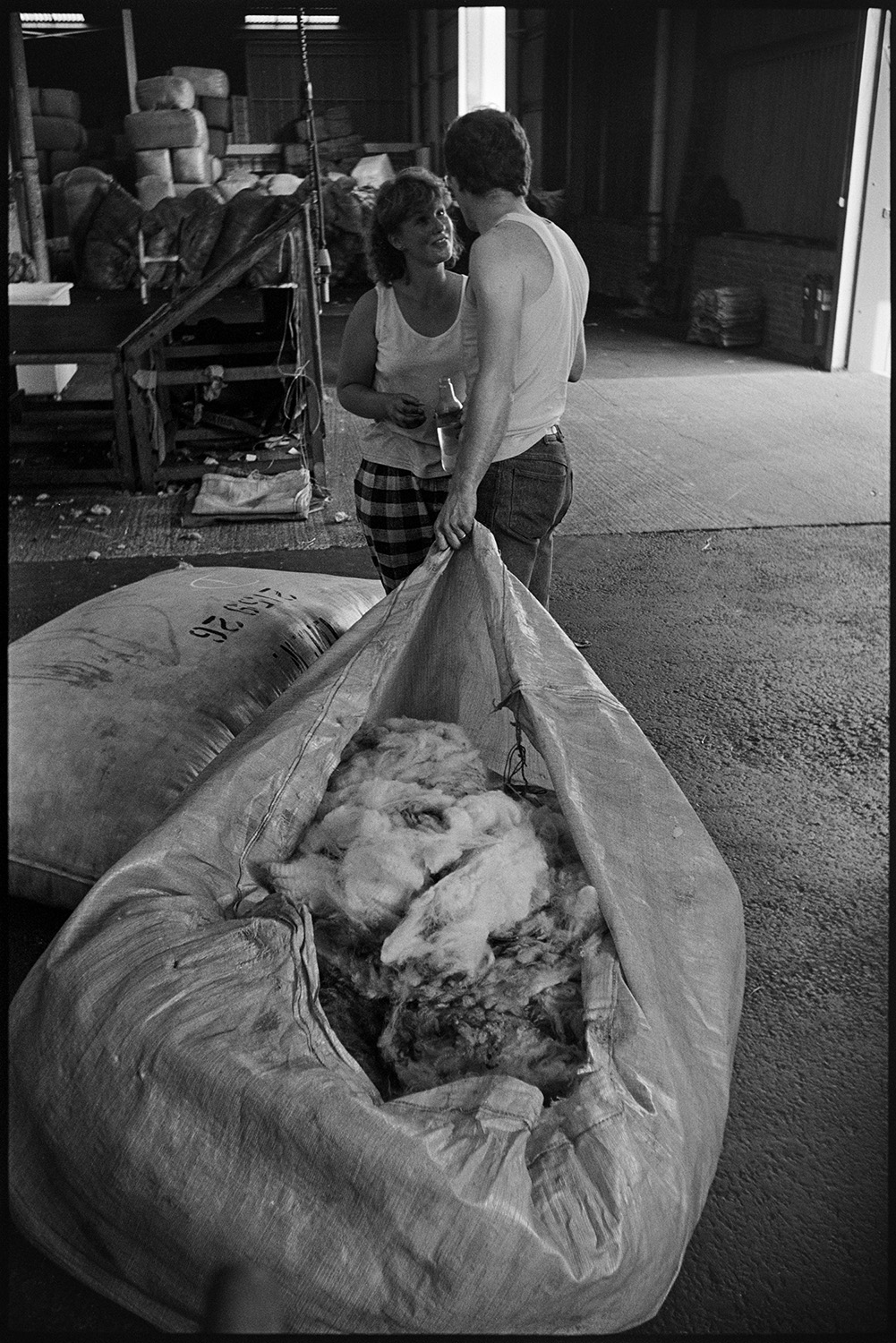 A man pulling an opened bag of wool and talking to a woman in the warehouse of Devon & Cornwall Wools Ltd at the Pathfields Business Park in South Molton.
