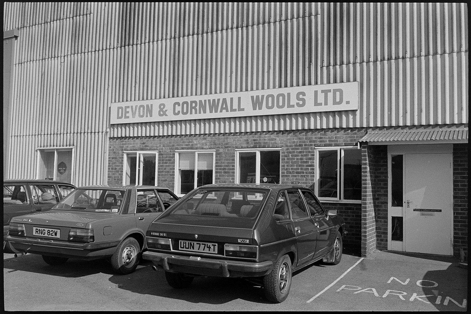 Front of wool merchants warehouse with sign.
[Cars parked outside the warehouse of Devon & Cornwall Wools Ltd at the Pathfields Business Park, South Molton.]