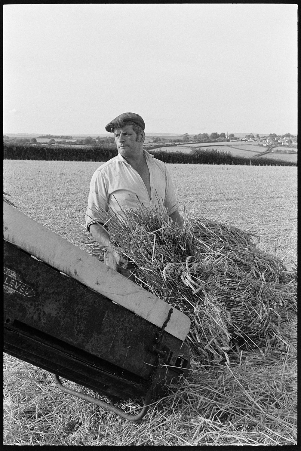 Reedcombers having tea break and working reed comber. 
[A man, possibly from the Down family, loading an elevator with bundles of reed to be transported to a reed comber, in a field at Spittle Farm, Chulmleigh.