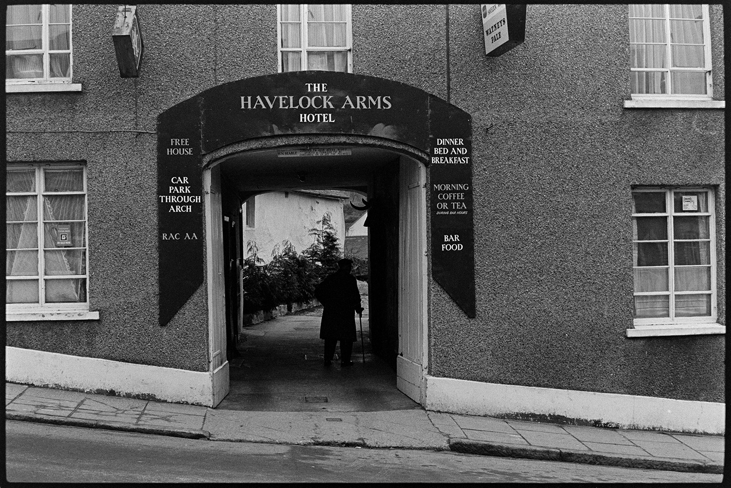 Entrance to pub.<br />
[An elderly person with a walking stick going through the main entrance to the courtyard of The Havelock Arms Hotel, Market Street, Hatherleigh.]