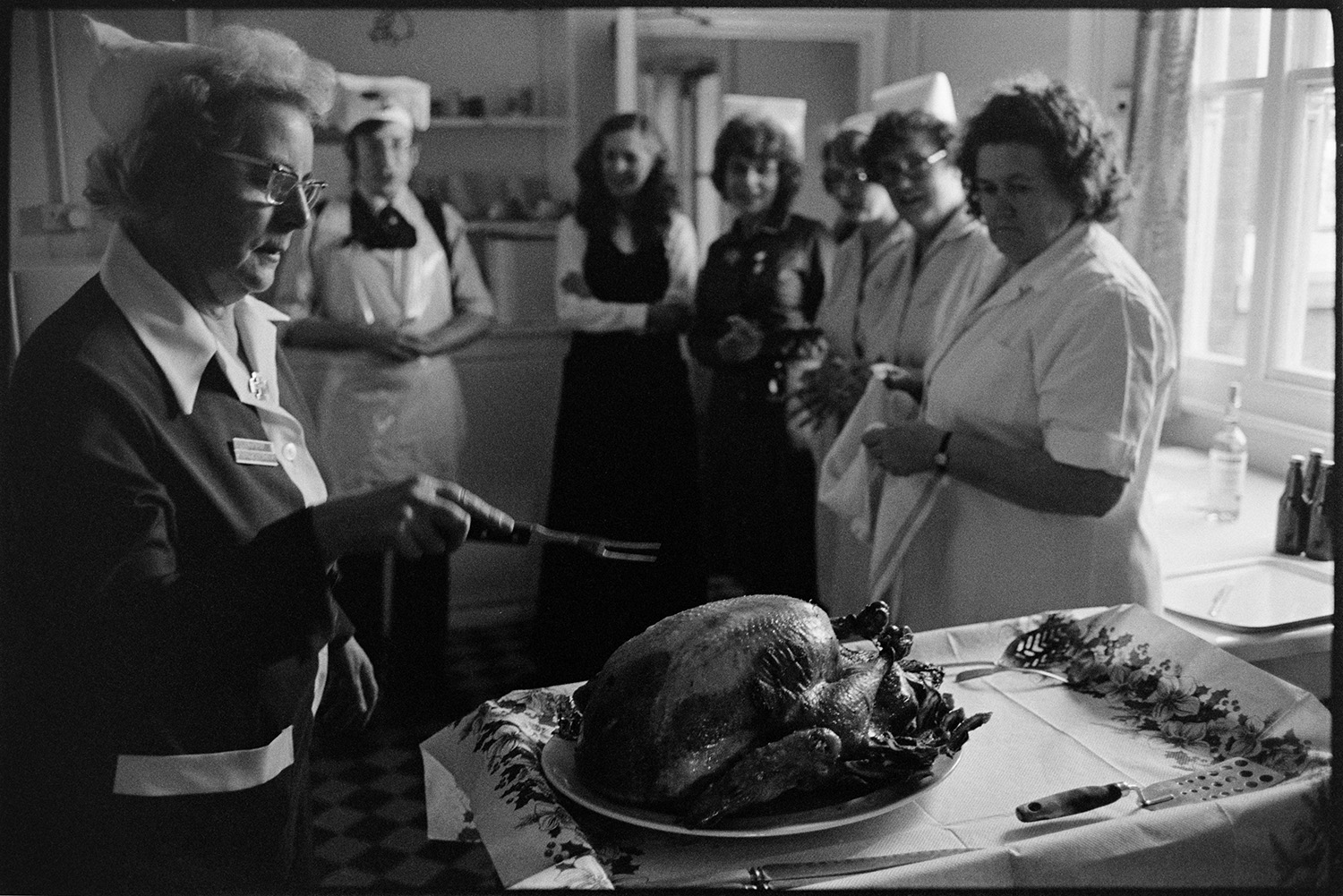 Doctor and nurses serving turkey dinner in hospital ward, Christmas Day.<br /> [A nurse about to carve a roast turkey at Torridge View Welfare Home in Torrington, for the staff and patients on Christmas Day. Other nurses and Doctor Paul Bangay are watching in the background.]
