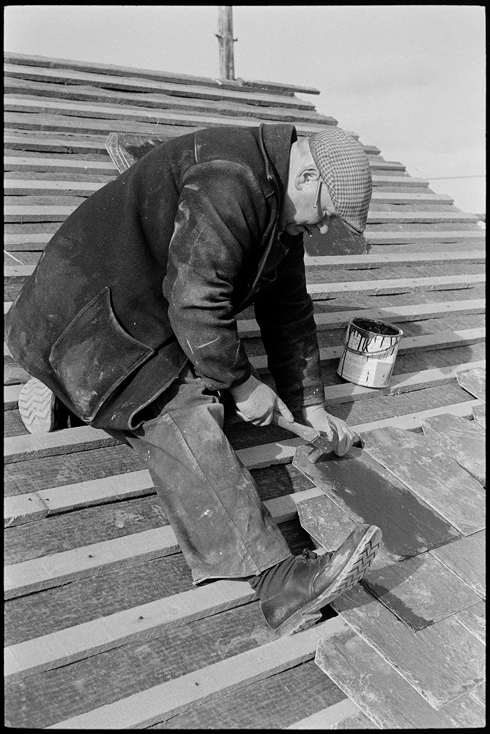 Man slating roof. 
[Ray Hutchins nailing slates to a roof at Langlands, Iddesleigh.]