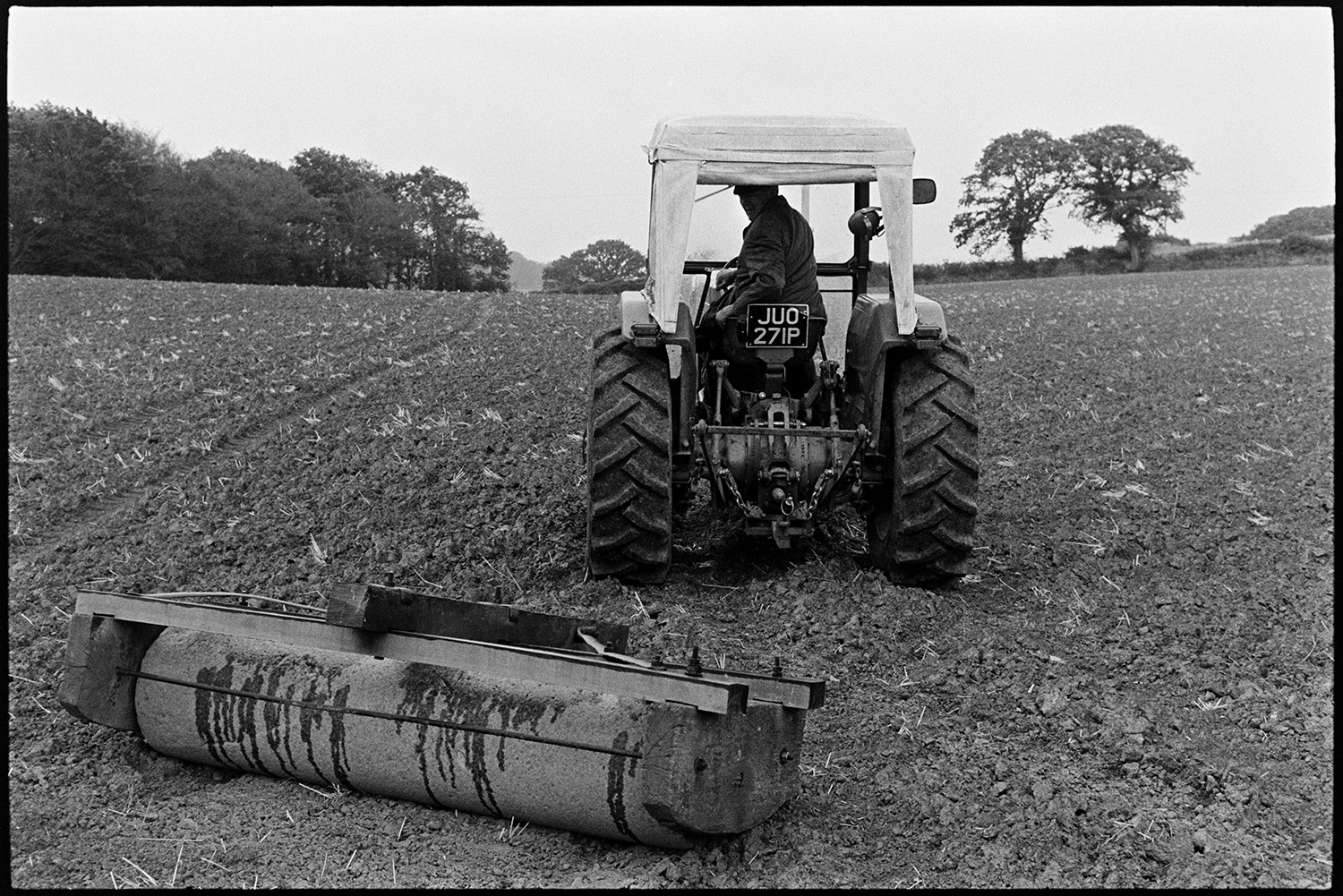 Rolling field with tractor. 
[John Ward driving a tractor pulling a roller over a field at Parsonage, Iddesleigh.]
