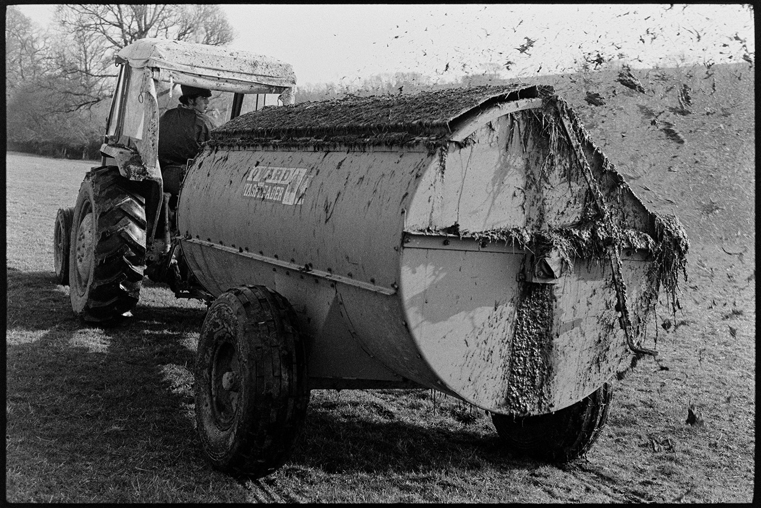 Muck spreader at work. 
[A member of the Ward family muckspreading in a field at Parsonage, Iddesleigh.]