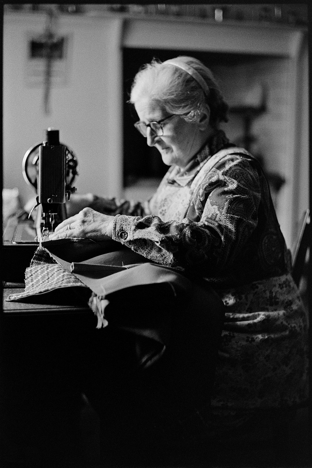Woman using sewing machine. 
[Norah Maynard using a manual sewing machine in her home at Atherington.]