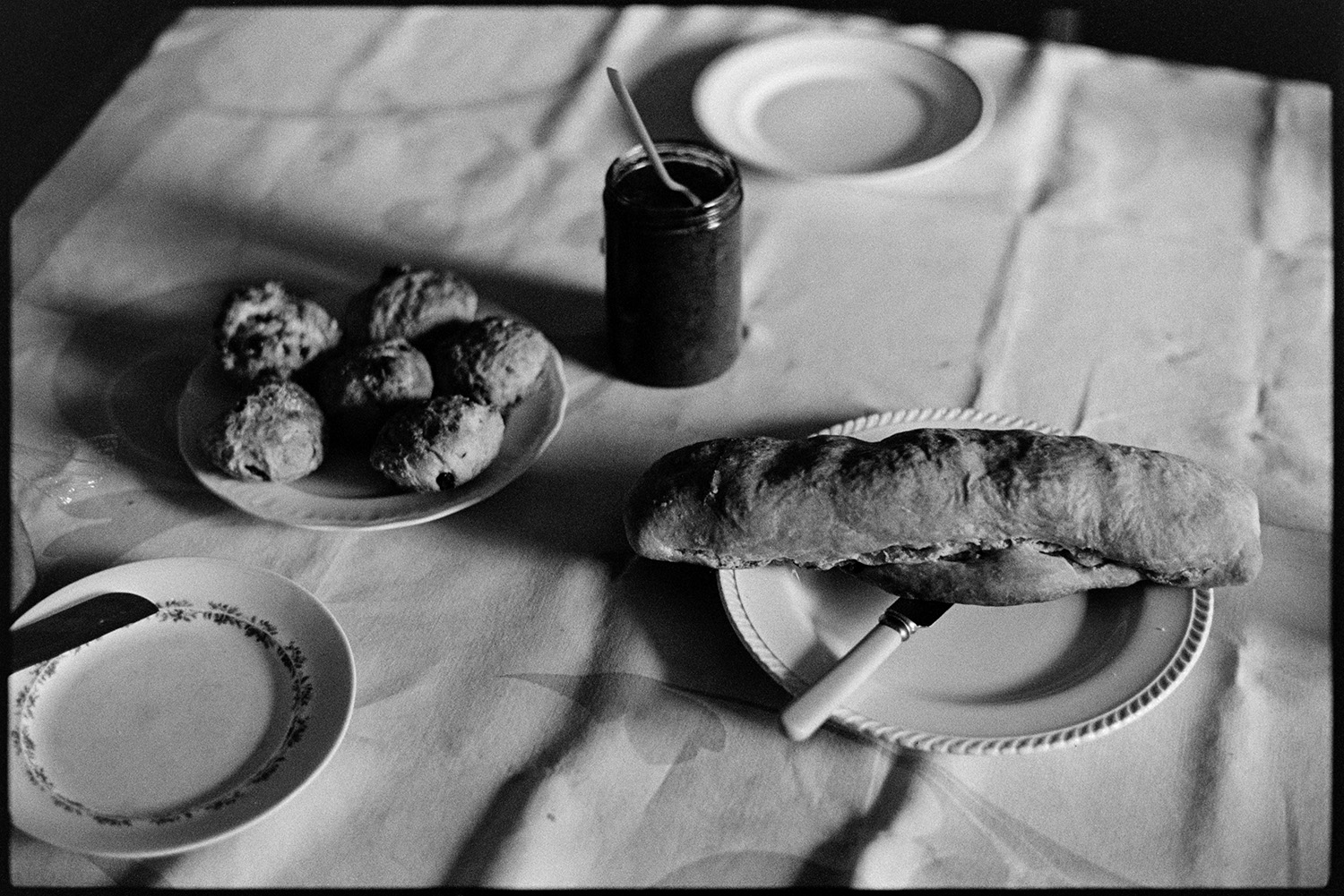 Home made bread, buns and pickle on table. 
[Norah Maynard's homemade bread, cakes or scones and pickle on a table in her house in Atherington.]