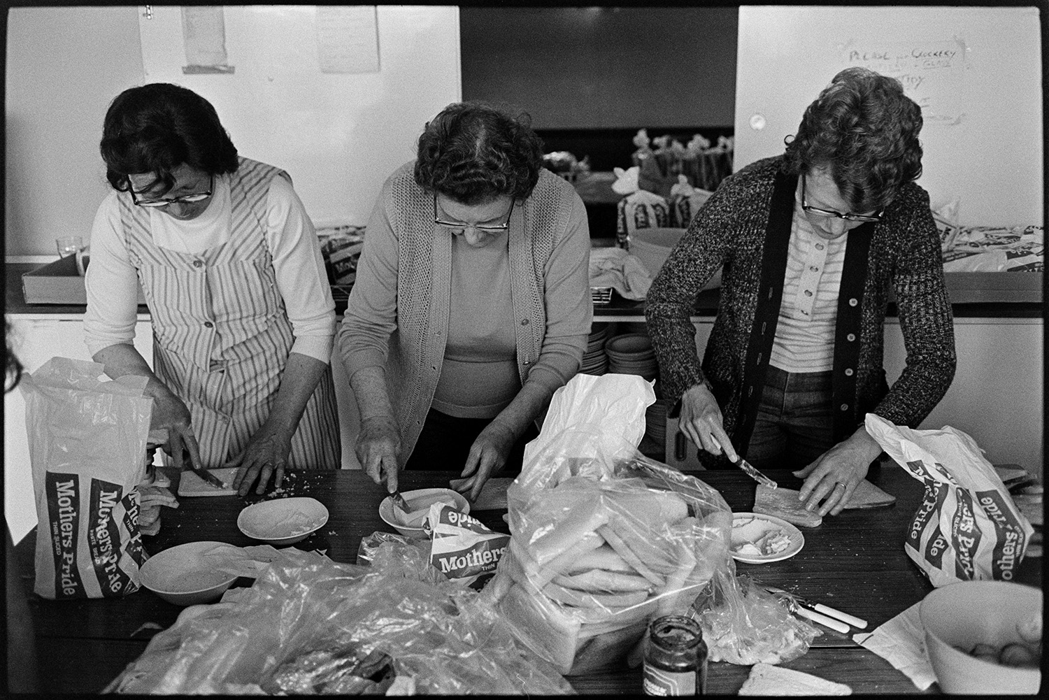 Women making sandwiches for Jubilee tea, on jubilee day! 
[Mrs Dark, on the left, and two other women making sandwiches for the celebrations for Queen Elizabeth II Silver Jubilee day at Dolton Village Hall.]