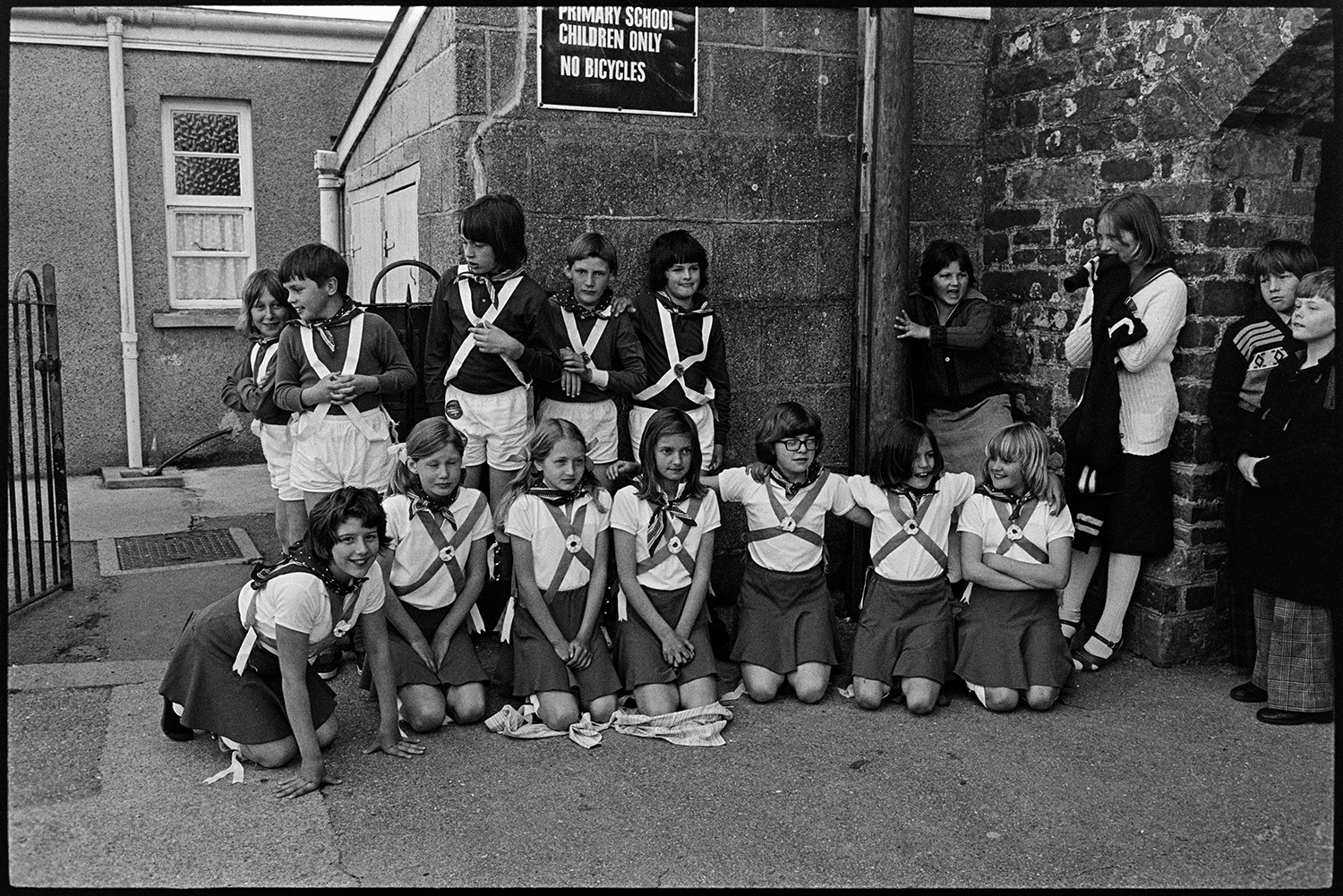 Children Morris dancing in village street. 
[Child Morris Dancers posing for a photograph at High Bickington Primary School before performing in the celebrations for the Silver Jubilee of Queen Elizabeth II.]