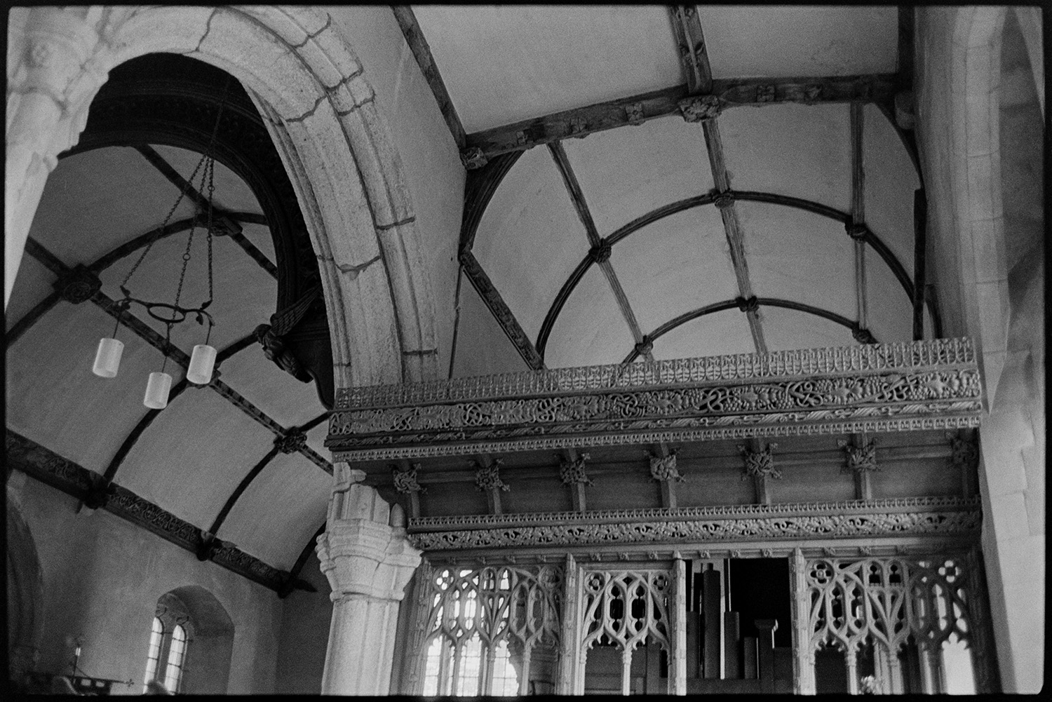Interior and exterior of Church with fine ceilings. 
[The interior of the church at Sampford Courtenay. A carved wooden screen and vaulted ceiling are visible.]