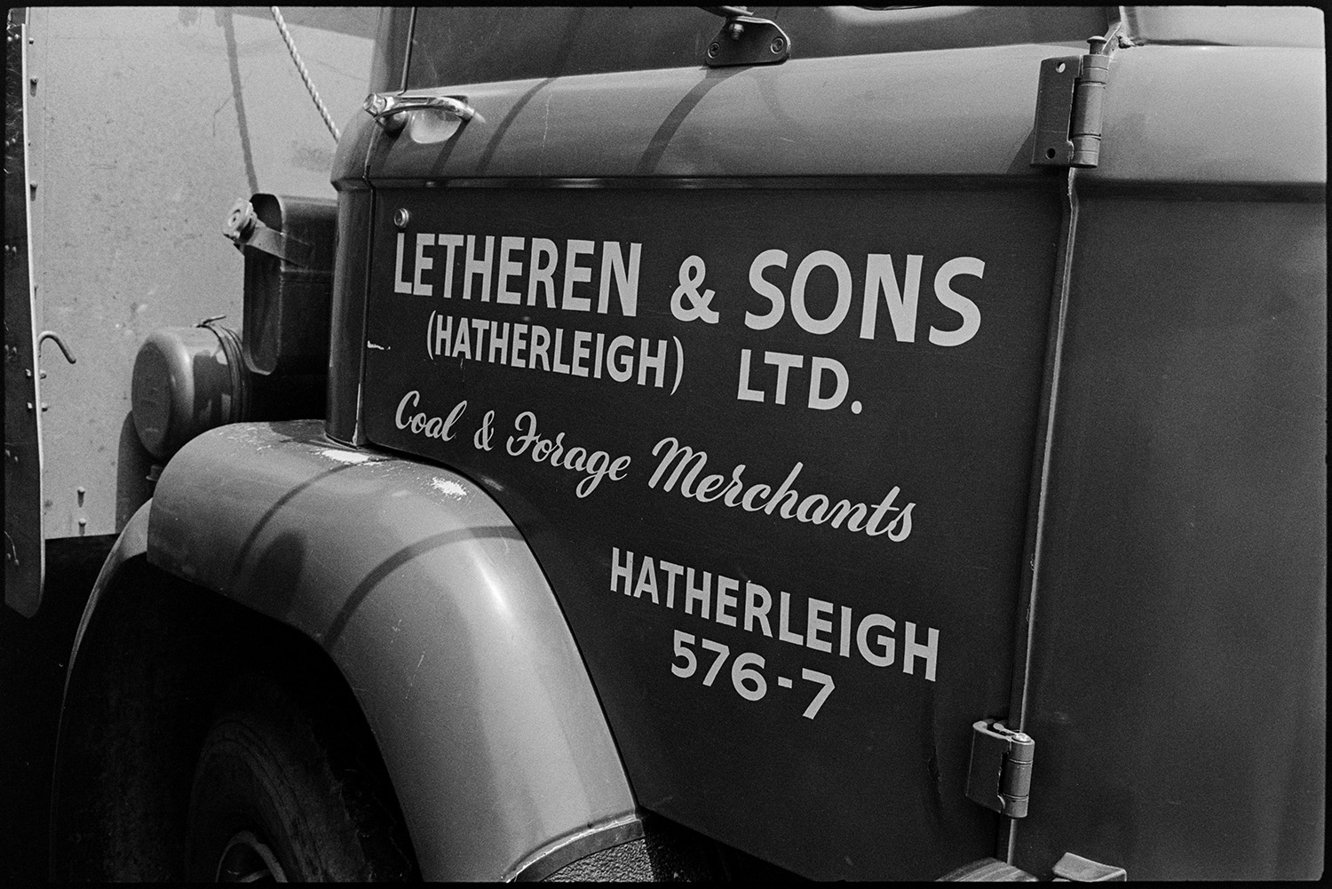 Sign on lorry. 
[The sign painted on a Letheren & Sons lorry reading 'Letheren & Sons (Hatherleigh) Ltd. Coal & Forage Merchants' at Hatherleigh Monument.]