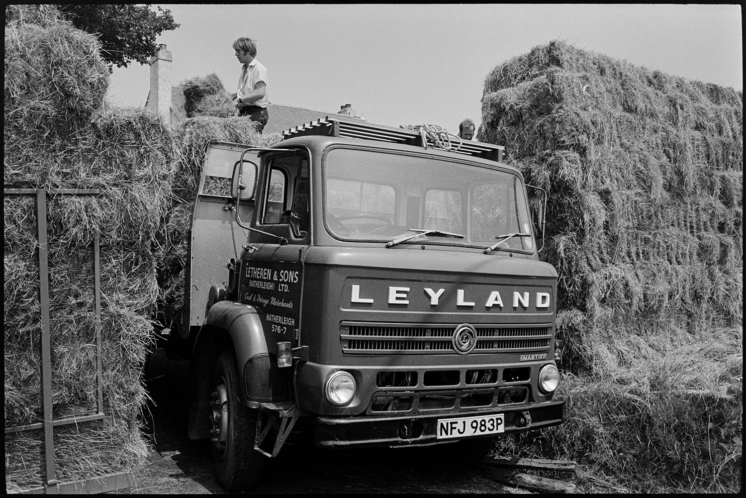 Sign on lorry. 
[Men loading hay bales onto a Letheren & Sons lorry at Hatherleigh Monument.]