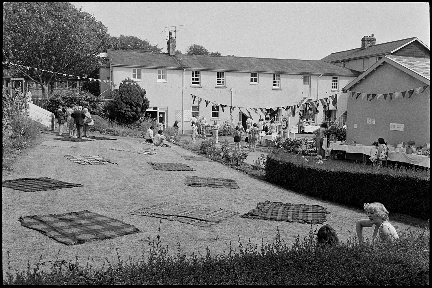 Scenes at opening of barbeque fete in grounds of sheltered homes, pony ride, roulette, etc. 
[People at a fete at Torridge View sheltered housing in Torrington. Stalls, games and picnic rugs can be seen in the grounds. Bunting and flags are also hung up across the grounds.]
