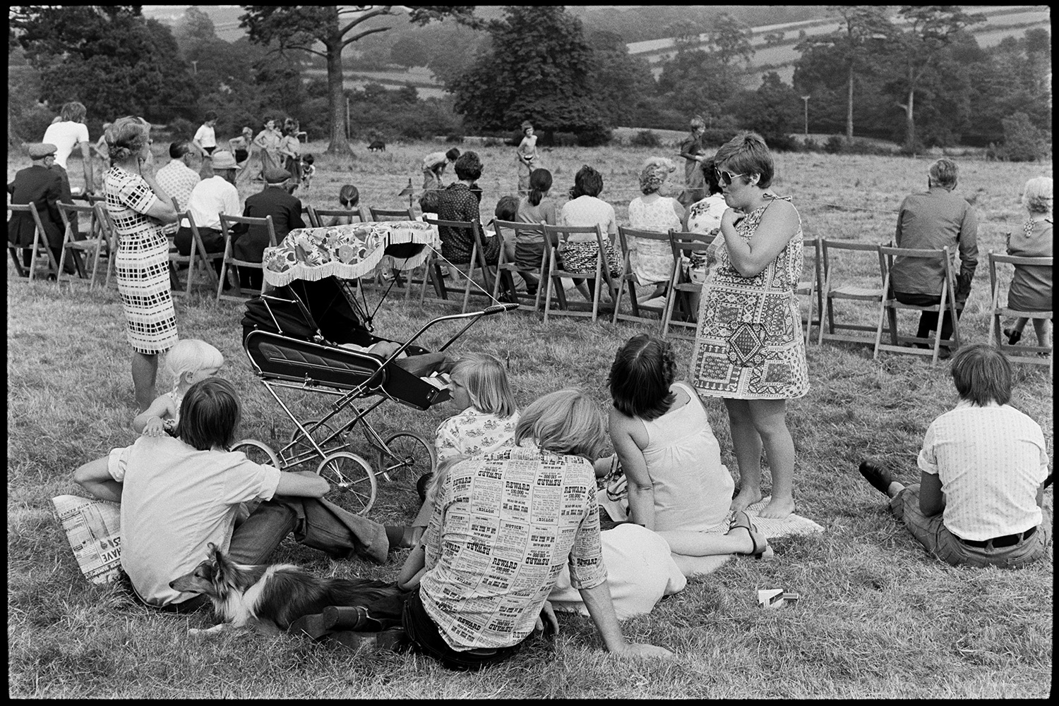 Open air concert, Beaford Event. 
[Spectators sat on chairs in a field at Nethercott, Iddesleigh waiting for an open air concert by Michael Nyman and his band. The event was organised by The Beaford Centre. A family are sat in the foreground with a pram and dog.]