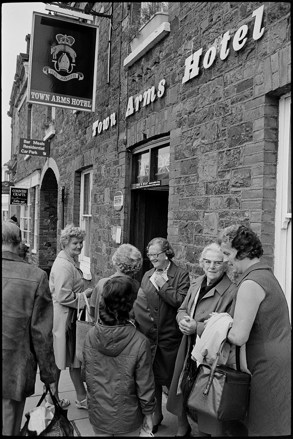 Street scenes, passers by. 
[A group of women talking outside the Town Arms Hotel at South Molton.]