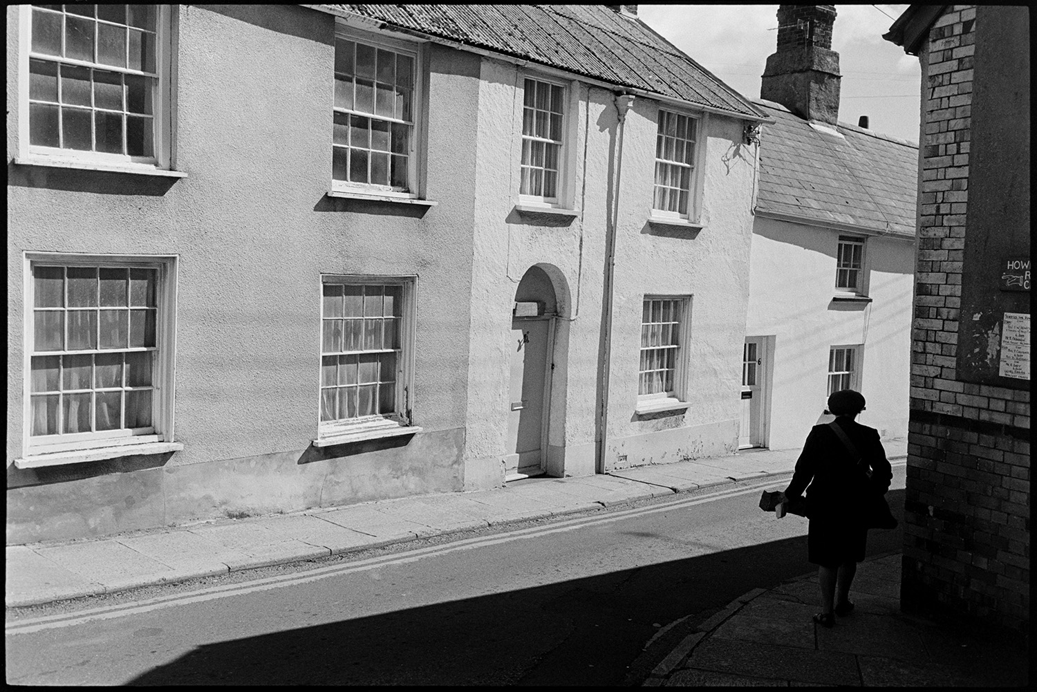 Street scenes with postwoman road sweeper and passers by. 
[Ms Bisset, a postwoman, walking along a street in Torrington past terraced houses.]