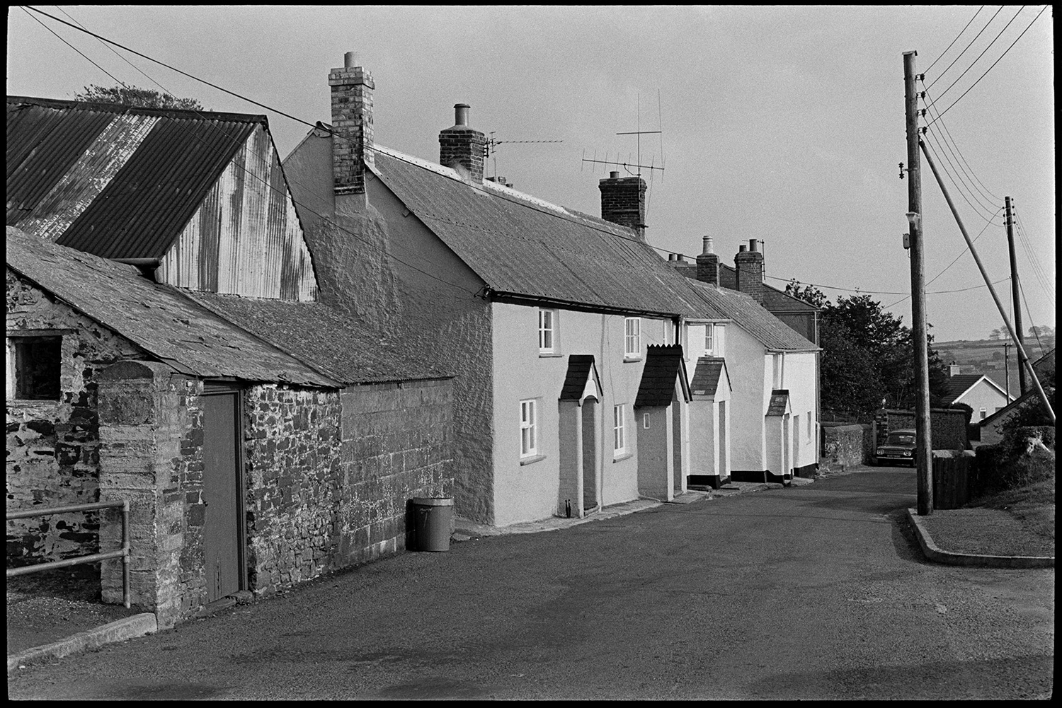 Houses taken to compare with photos in the old Archive by George Tucker. 
[A street in Peters Marland, Burrington with terraced houses and farm buildings. The houses each have a small porch.]