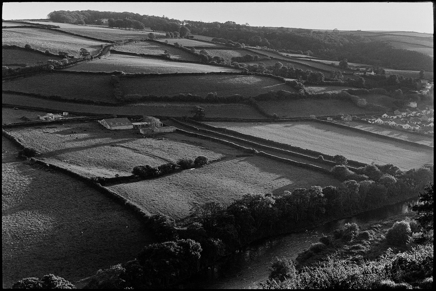 Landscape with ancient strip fields, or leper fields. 
[A landscape of fields, hedges, trees and farm buildings near Torrington. Old strip field can also be seen. The river Torridge is visible at the bottom of the frame.]