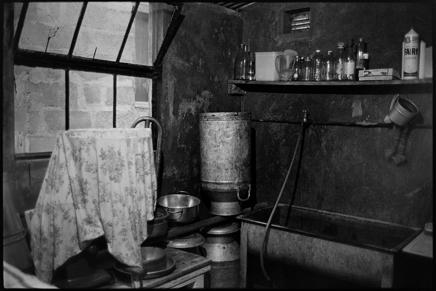 Equipment in dairy, churn etc. 
[Milking equipment in the dairy at Verdun, Atherington. A sink, milk churns and bottles are visible.]