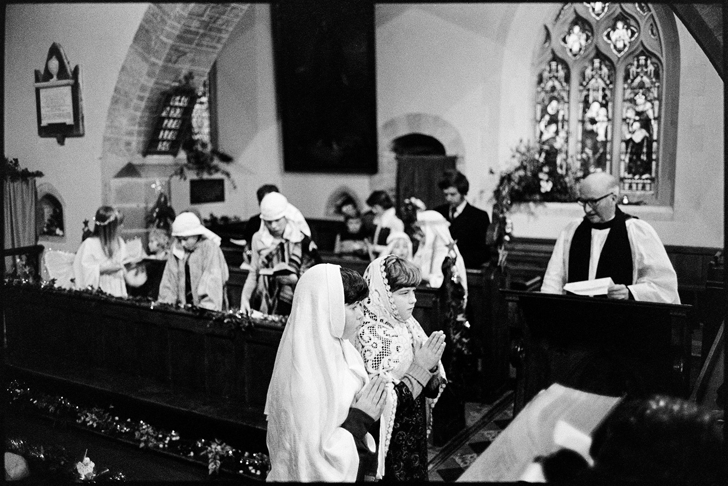 Nativity play, children in church. 
[Children performing in a nativity play at Dolton Church. Other children are dressed as angels and shepherds in the background, and are singing. The church is decorated for Christmas with tinsel.]