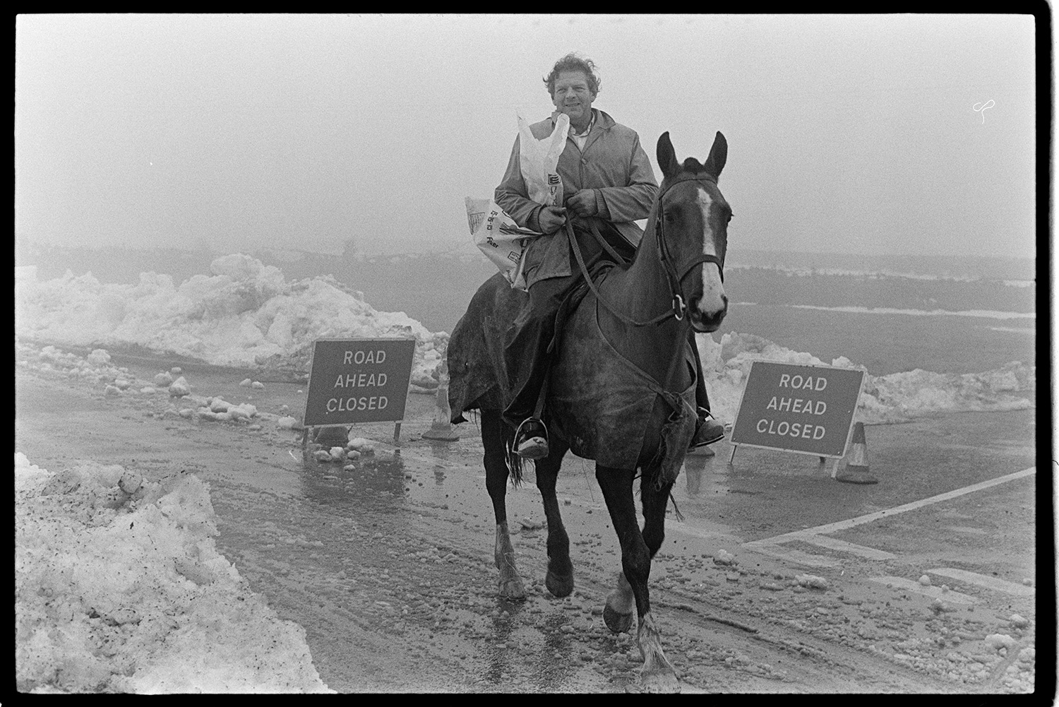 Snow, farmer on horse returning from village. 
[Dudley Middleton riding a horse along a road with snow at Dolton Beacon. He is returning from the village of Westacott. Sings on the road read 'Road Ahead Closed'.]