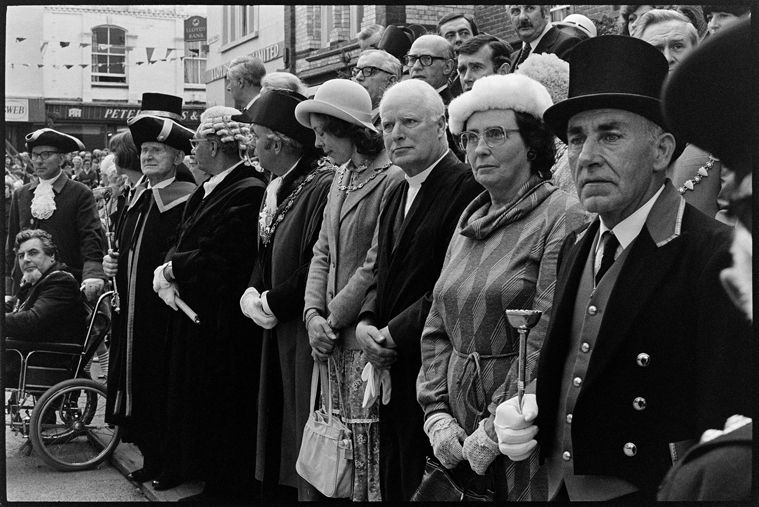 Mayors, wives and dignitaries in square looking at Mayfair parade. 
[Mayors, dignitaries and wives in Torrington square, watching the Mayfair parade. Dr Cramp is wearing his mayoral chain of office and a bicorne hat. A man in the foreground is wearing a top hat.]