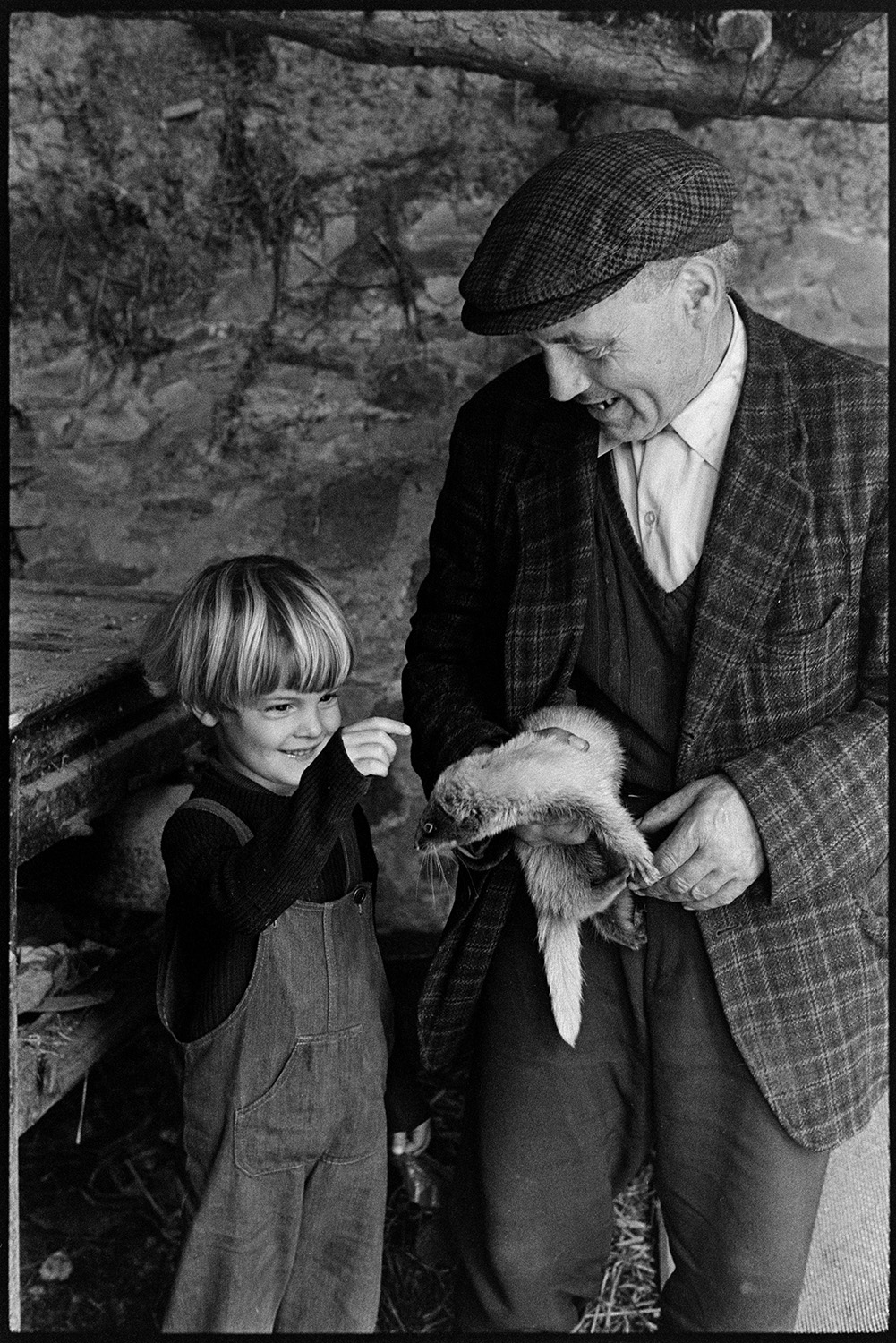 Farmer with ferret. 
[Ivor Brock showing Ben Ravilious his ferret in a barn at Millhams, Dolton.]