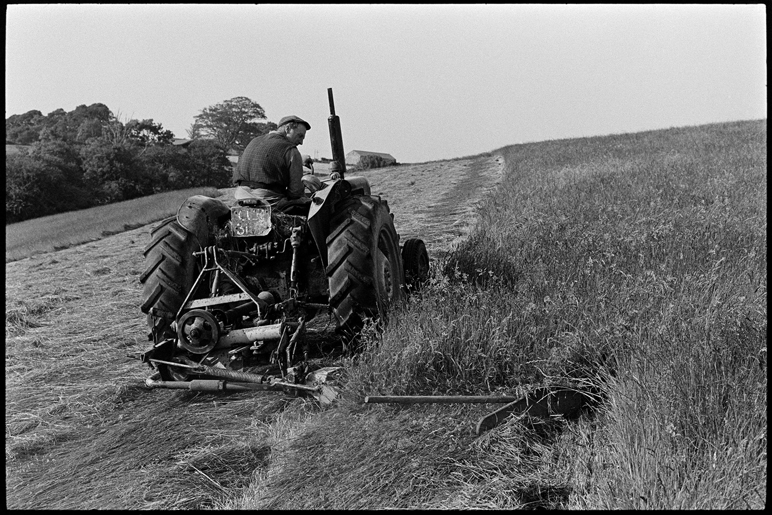 Farmer cutting grass, mowing. 
[George Ayre cutting grass with a tractor and mower in a field at Ashwell, Dolton.]