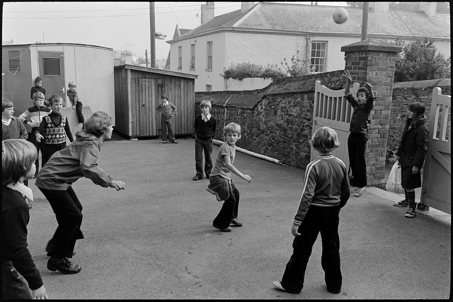 Children arriving at school and getting ready for assembly. 
[Children arriving at Blue Coats School, Torrington. They are playing in the school playground.]